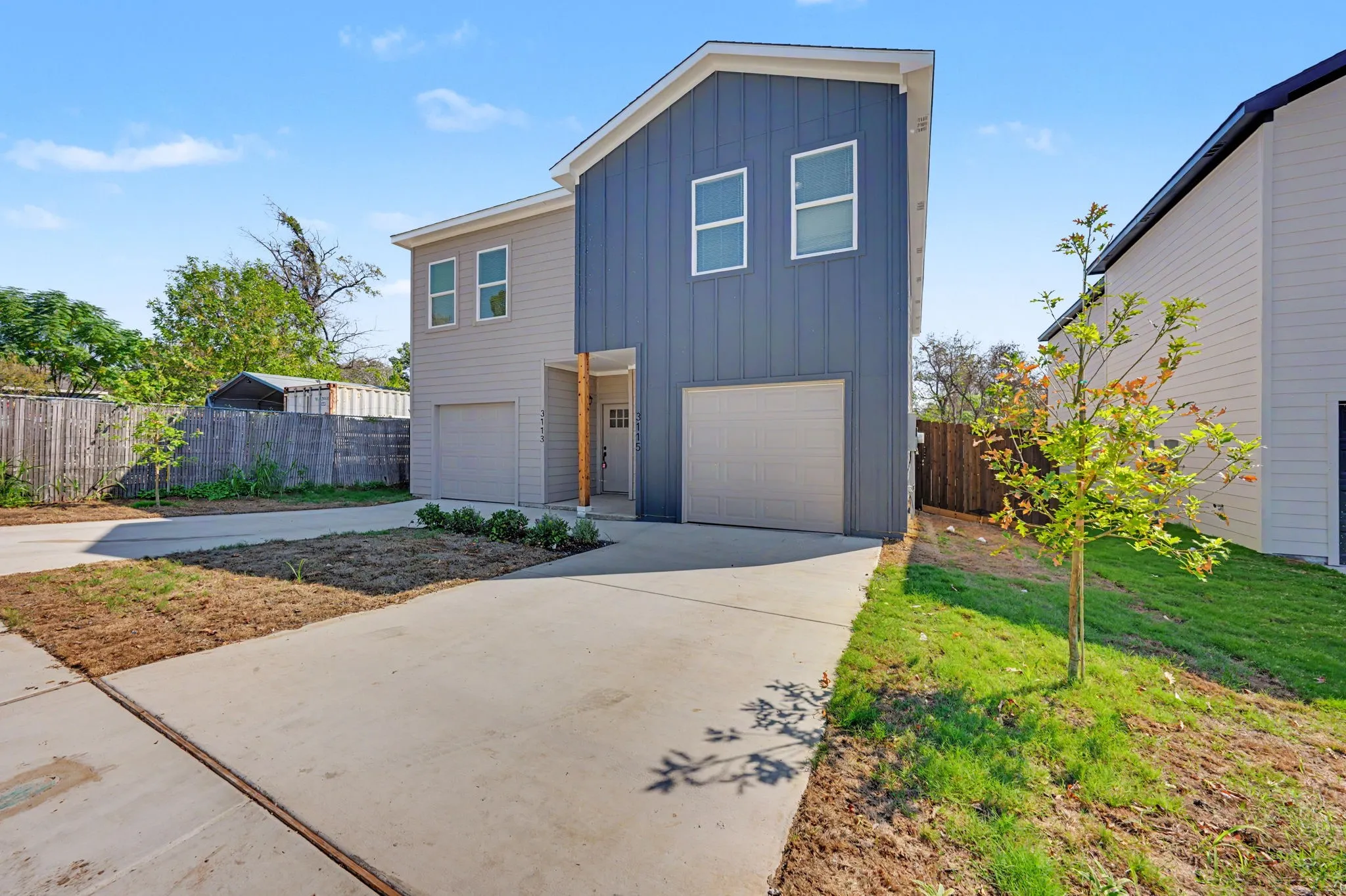 Modern exterior with board and batten siding, two-car garage, concrete driveway, and front landscaping