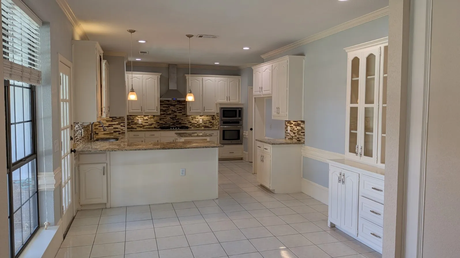 Kitchen featuring white cabinetry, stone countertops, a mosaic tile backsplash, stainless steel appliances, and tile flooring
