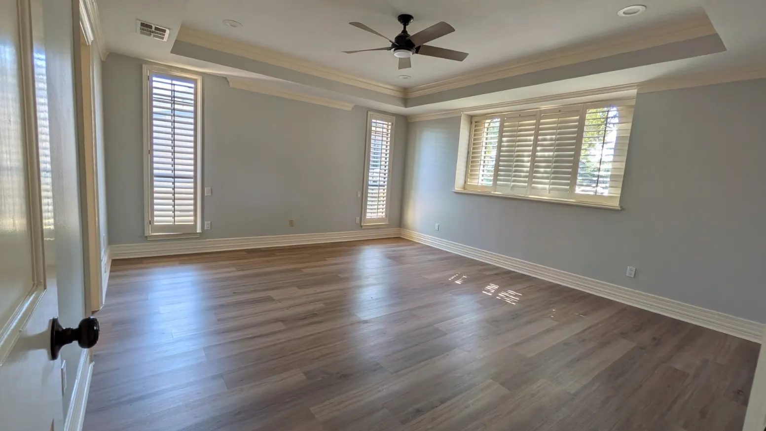 Wood-finish flooring, plantation shutters, tray ceiling, recessed lighting, and ceiling fan