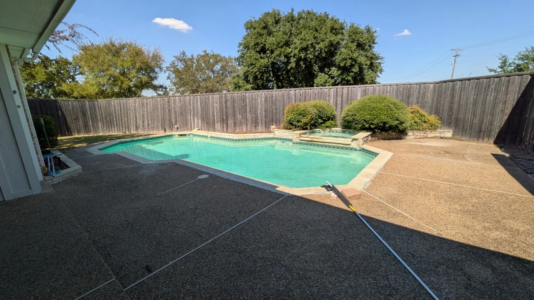 Expansive backyard featuring a blue-tiled swimming pool and a separate spa
