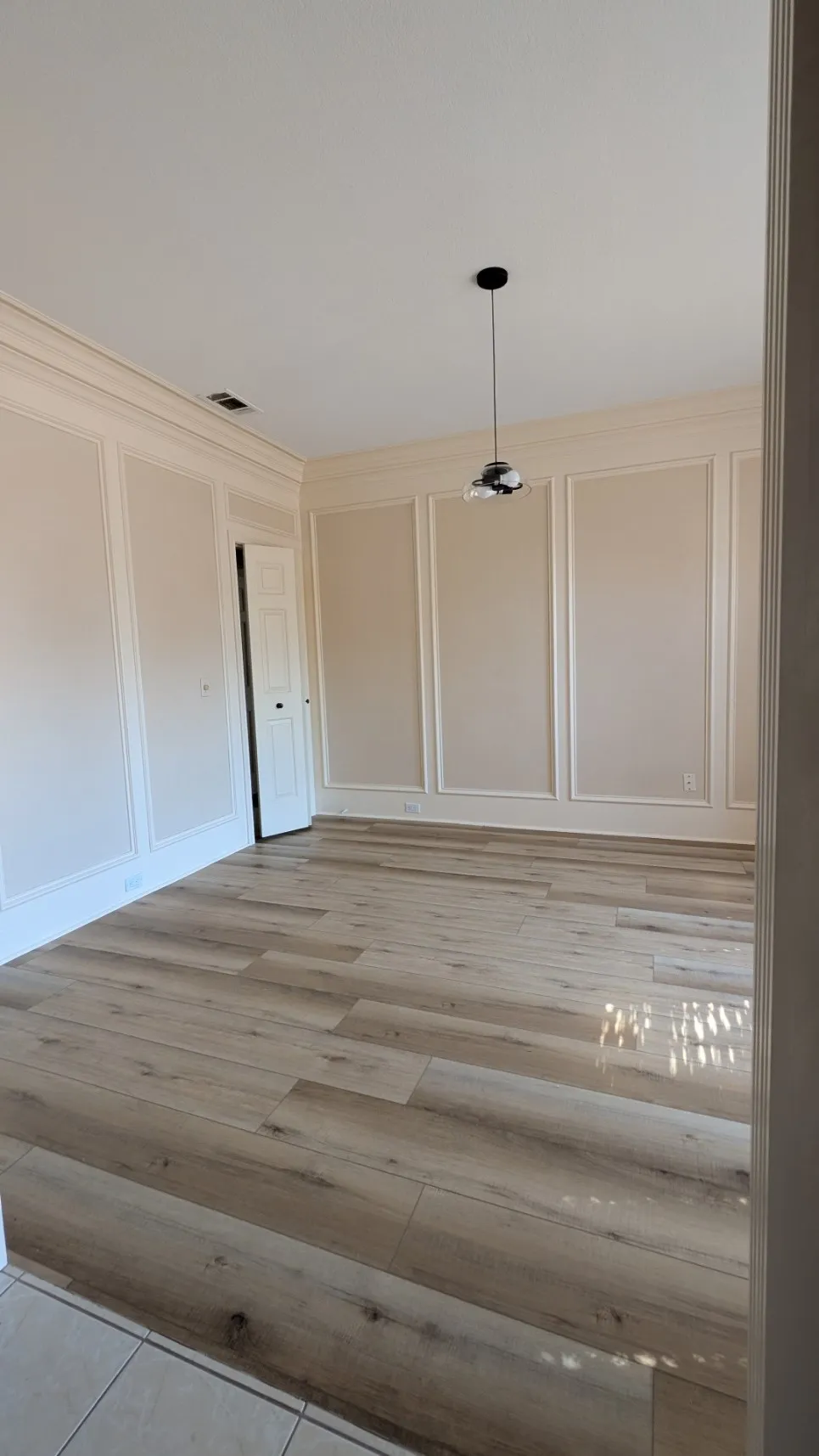 Wood-finish flooring, recessed lighting, crown molding, paneled walls, and a contemporary pendant light fixture