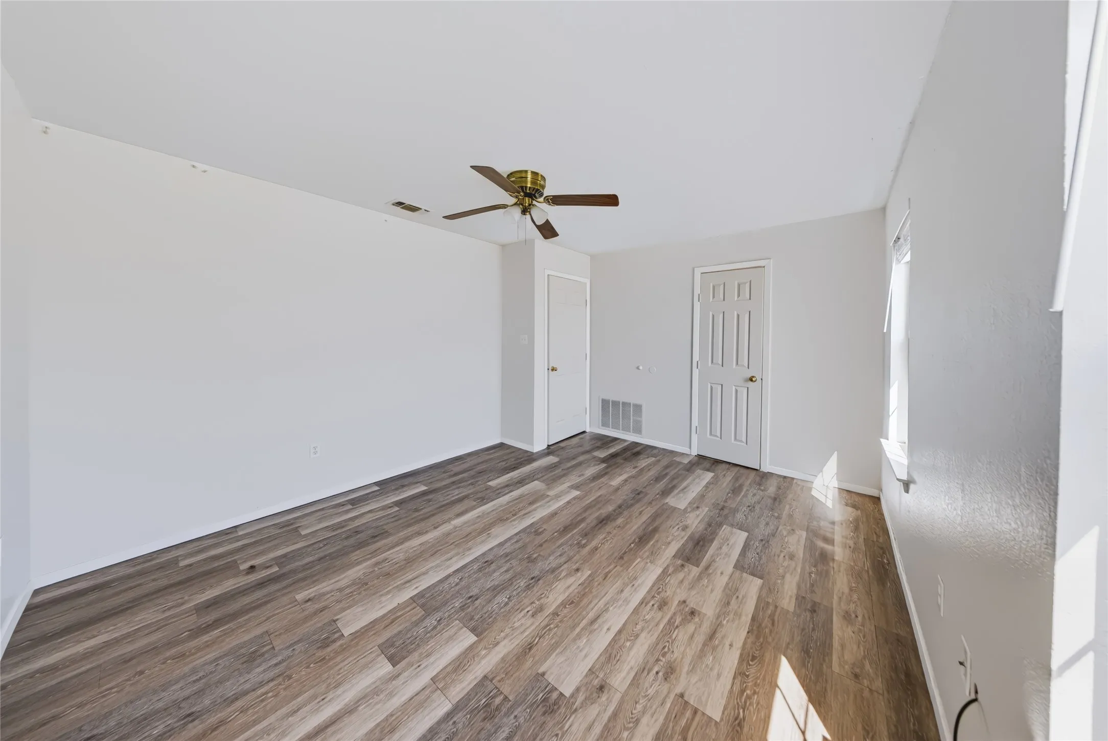 Main Home – Spacious interior with wood-finish flooring, ceiling fan, and crisp white walls