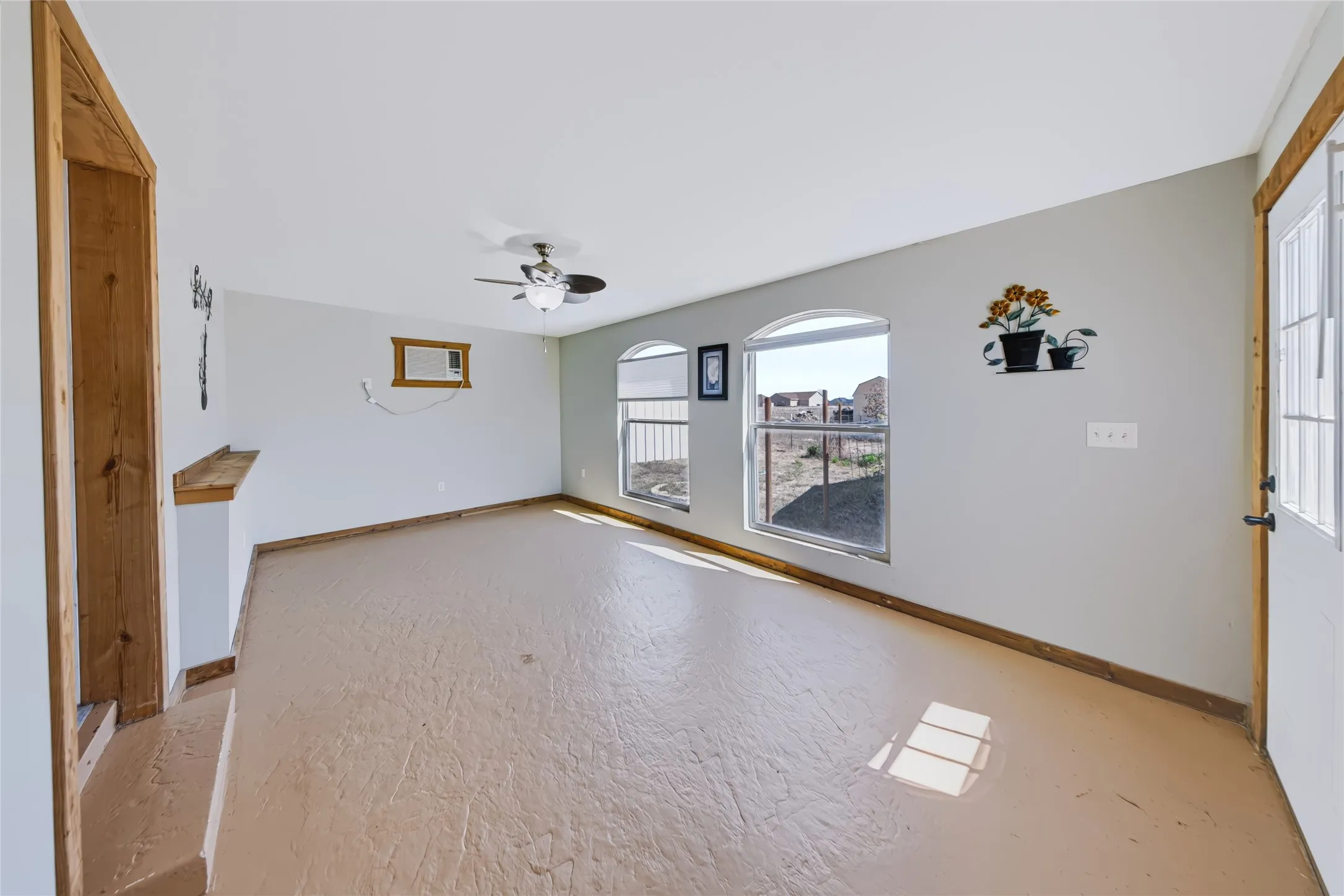 Second Home – Sunroom Arch-top windows, wood-finish trim, ceiling fan, and light-toned flooring