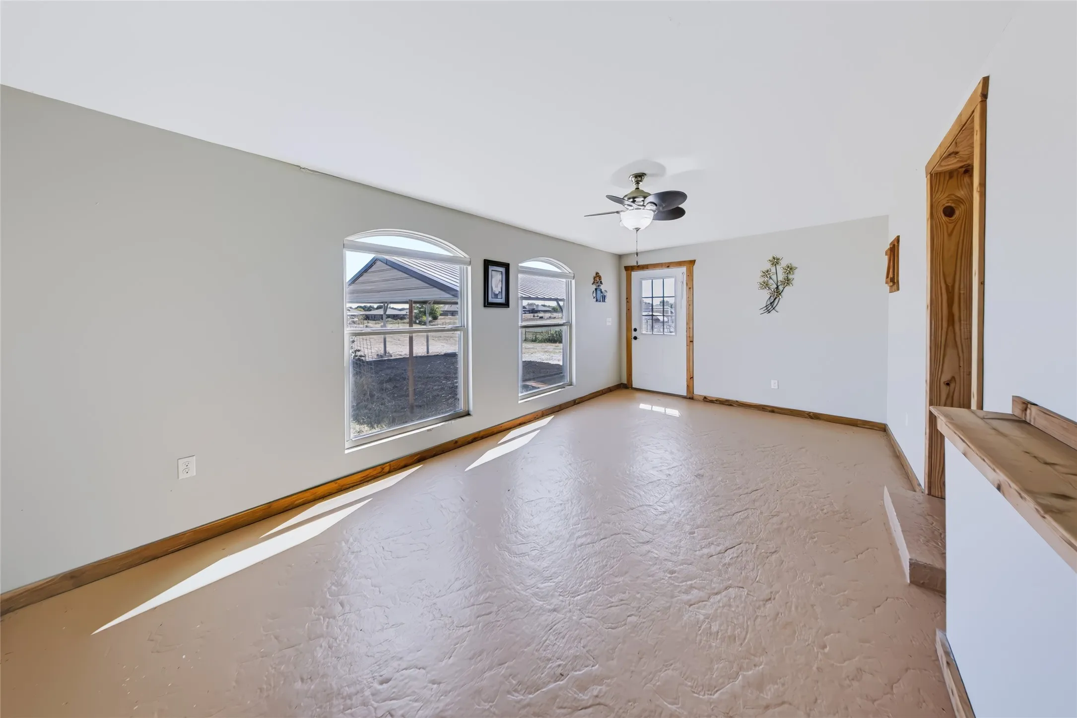 Second Home – door frames, textured concrete flooring, and a ceiling fan with light fixture