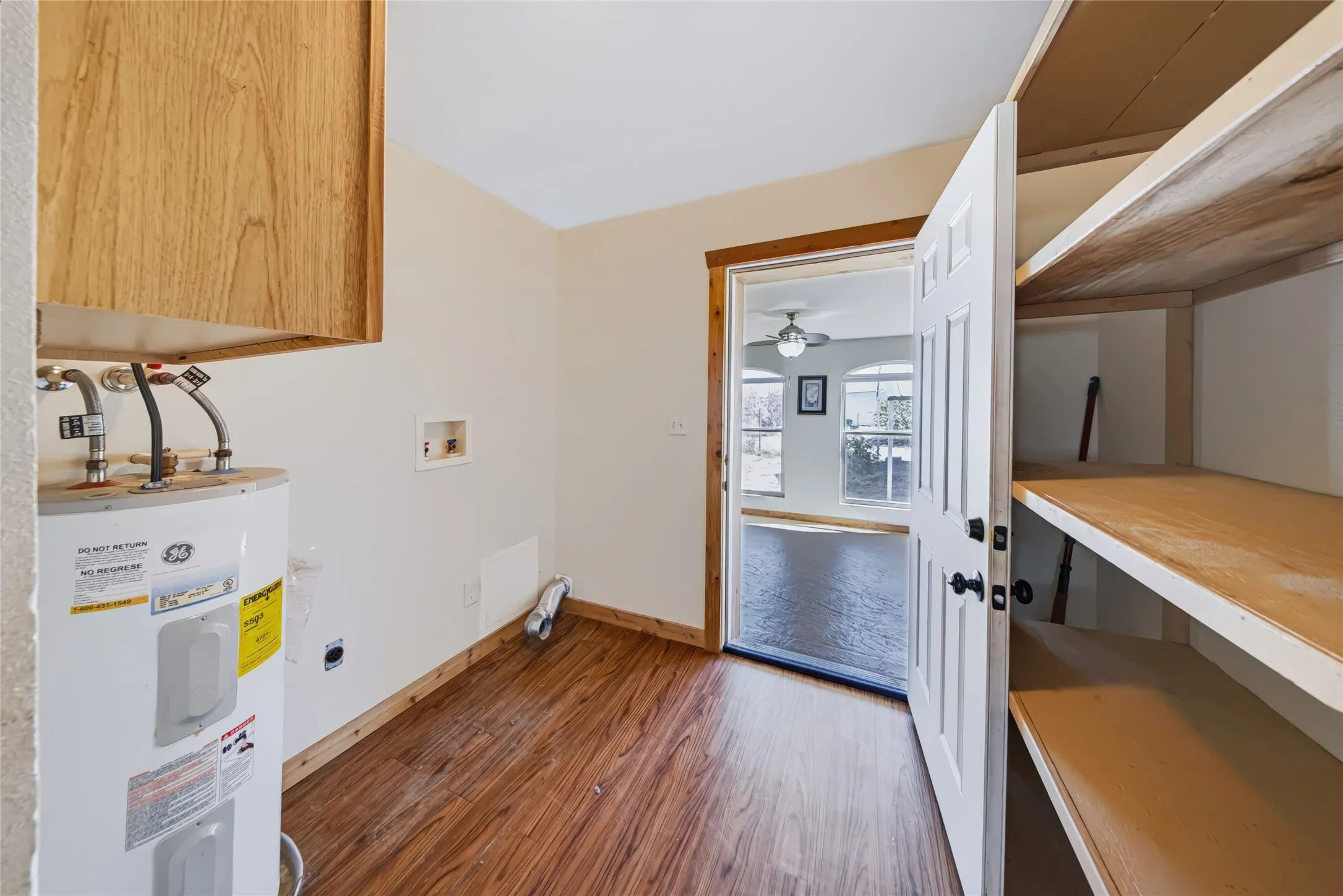Utility space with wood-finish flooring, built-in shelving, and a wood-paneled door frame