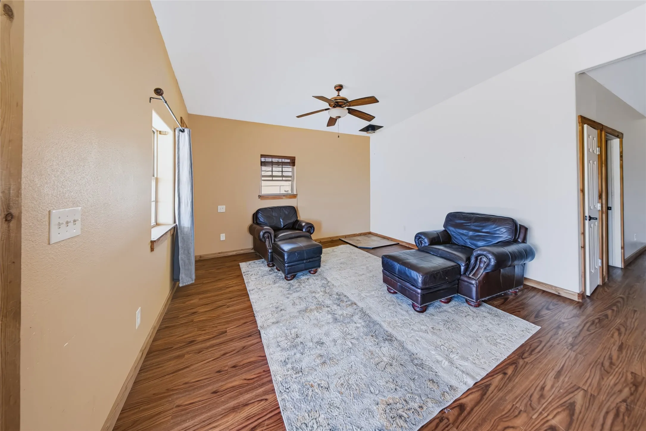 Vaulted ceiling with a ceiling fan, wood-finish flooring, and natural wood trim accents
