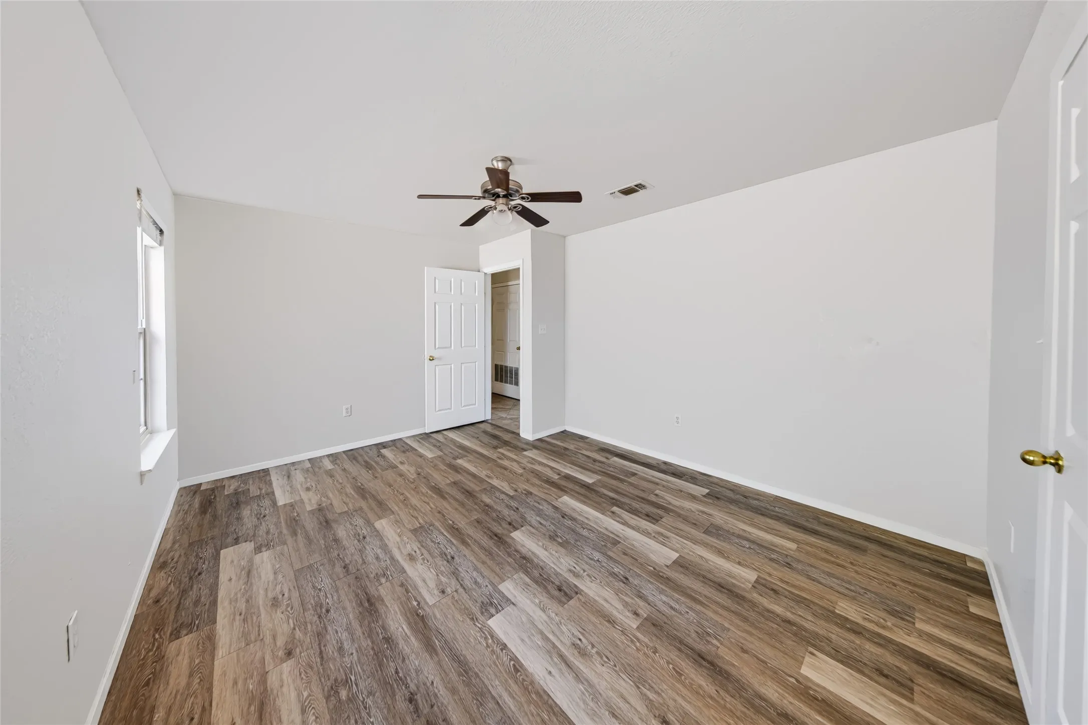 Main Home – Wood-finish flooring, white walls, and a ceiling fan with integrated lighting