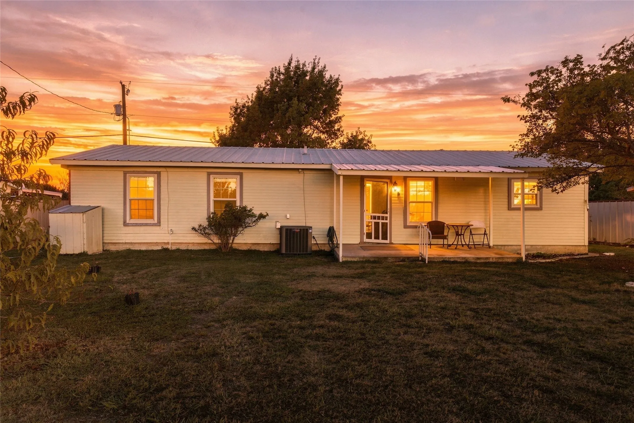 Single-story residence featuring light-colored siding, a metal roof, and a covered front porch