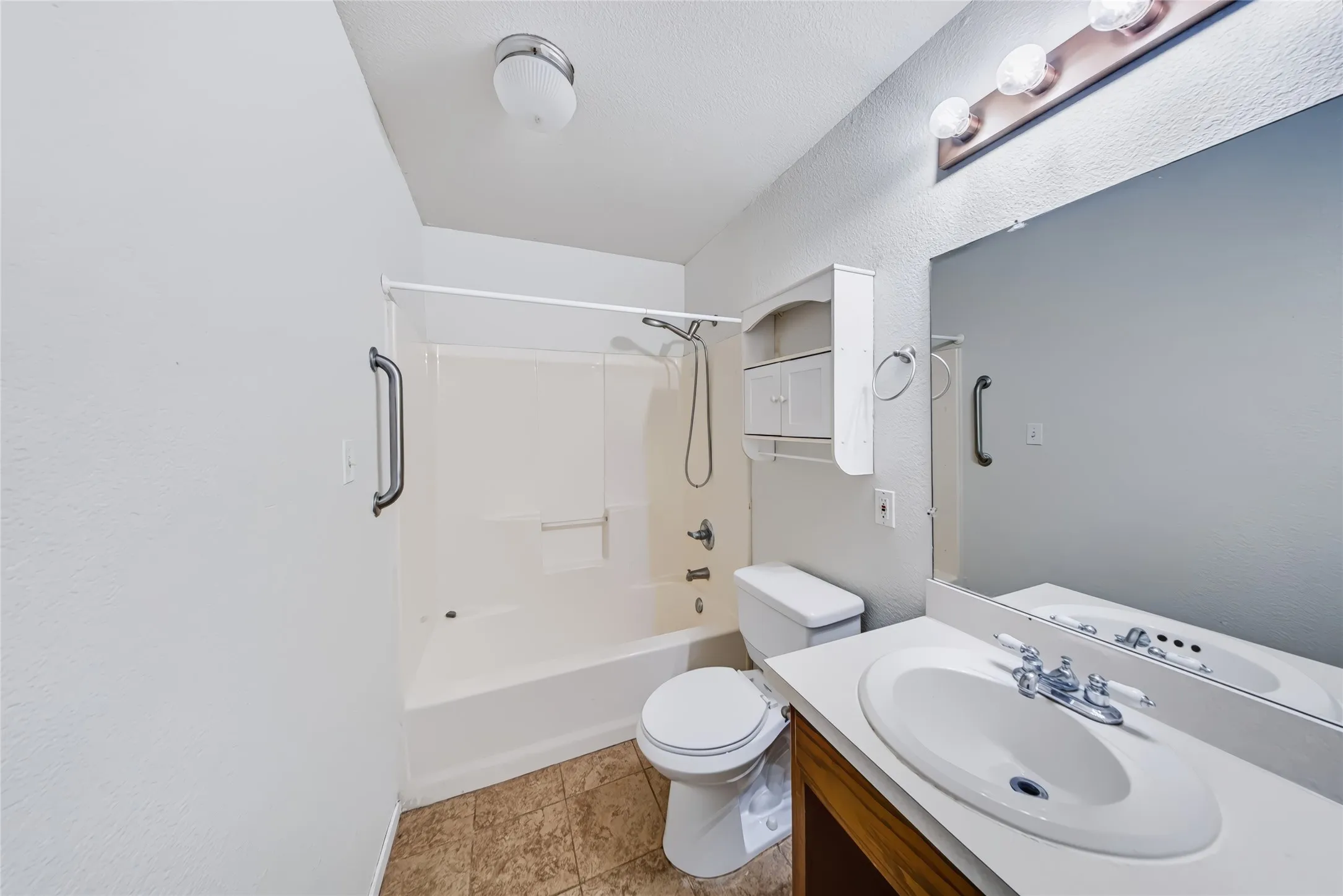 Bathroom with a single vanity, large mirror, and full bathtub with shower