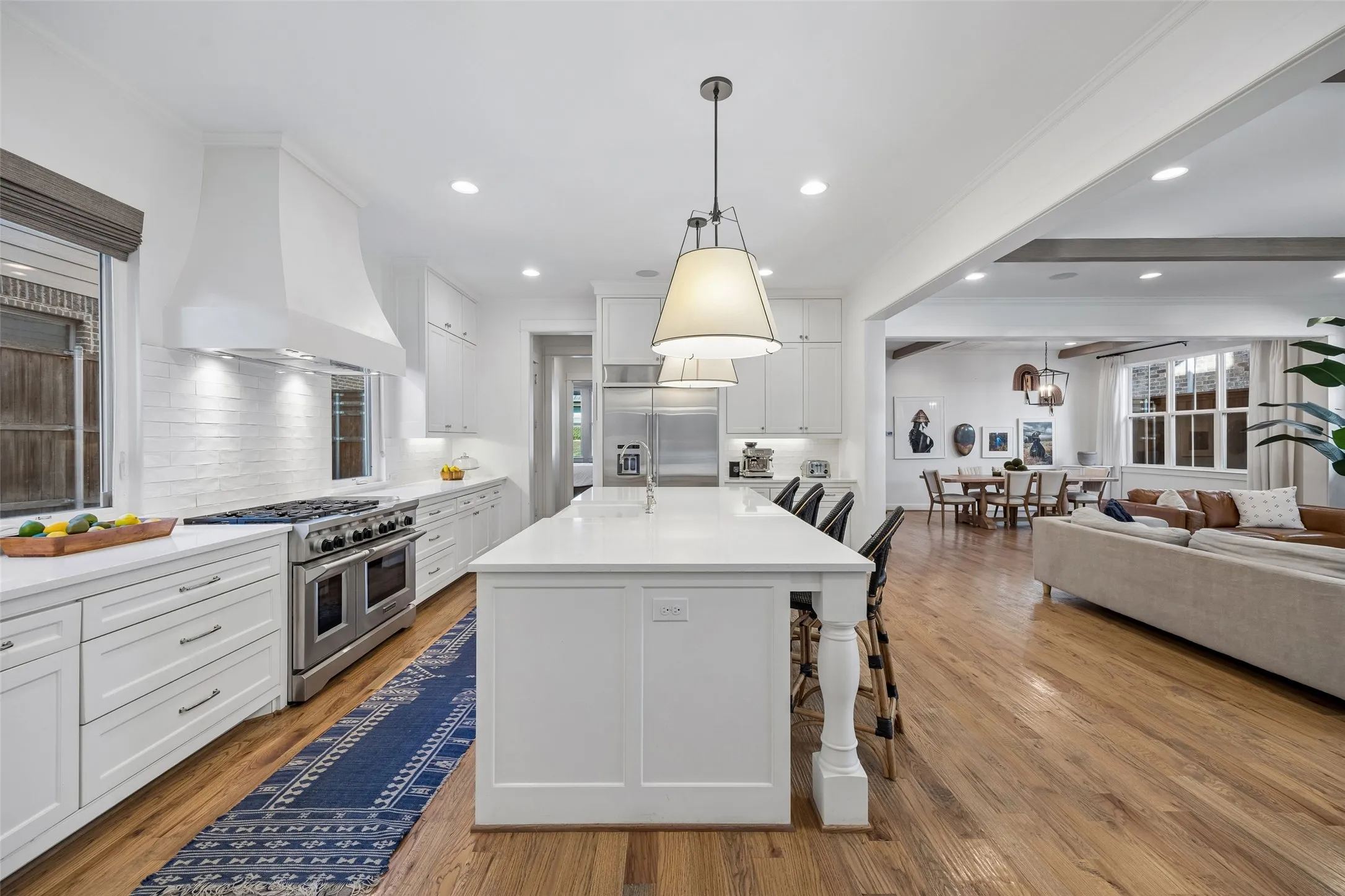 Open white on white kitchen with beautiful quartz countertops, Viking gas range and built in stainless steel refrigerator.