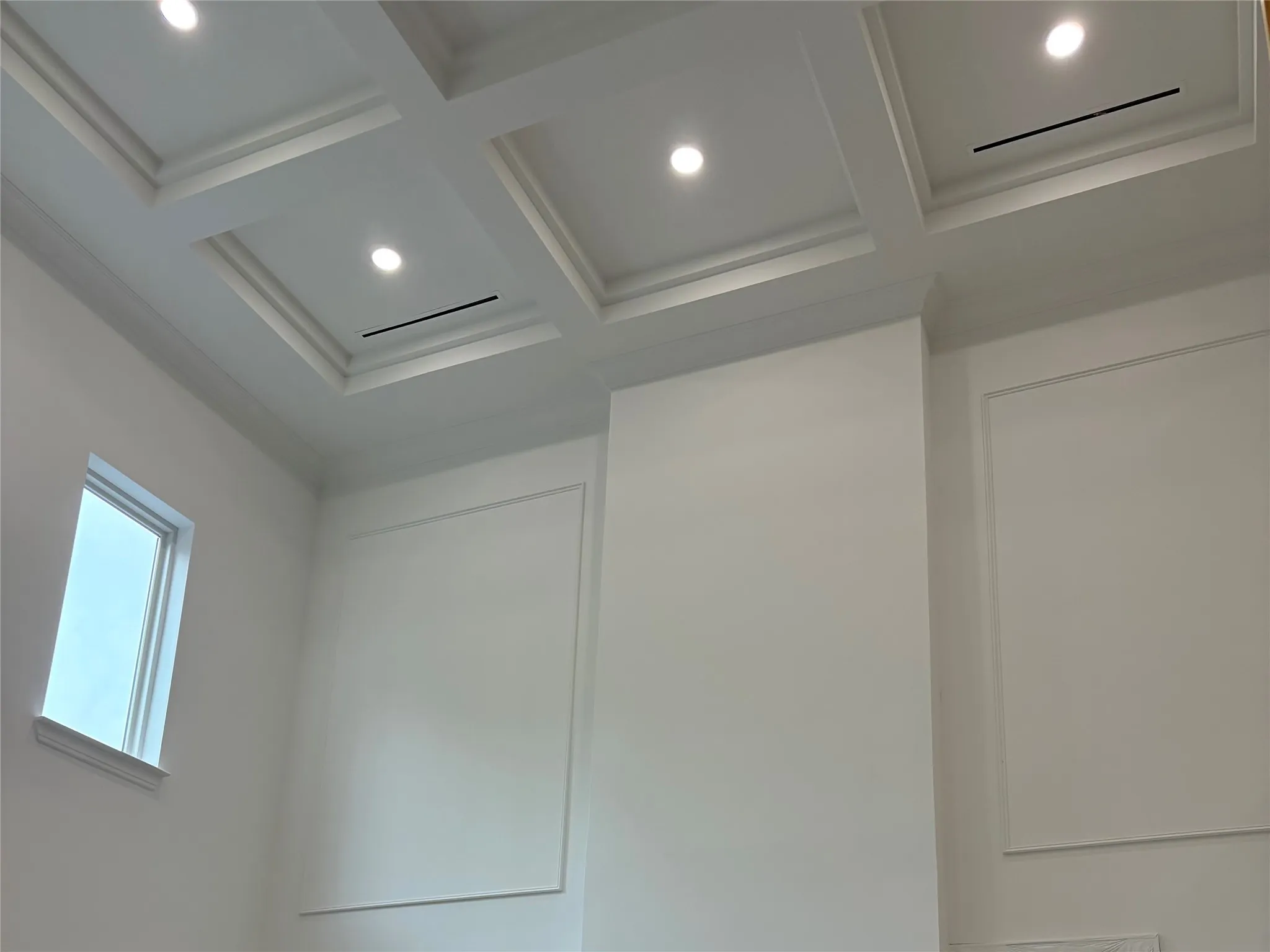 Coffered ceiling with recessed lighting, crown molding, and wall paneling