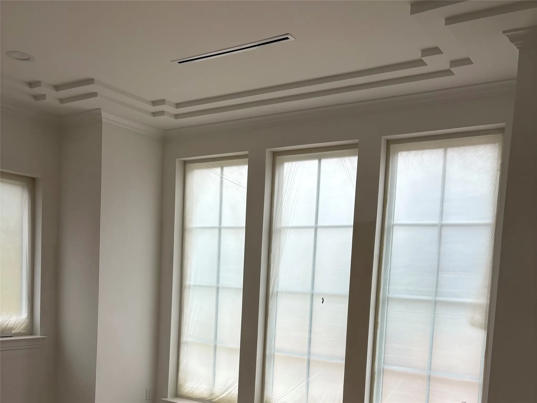 Recessed lighting, linear air register, tiered crown molding, and multiple grid windows