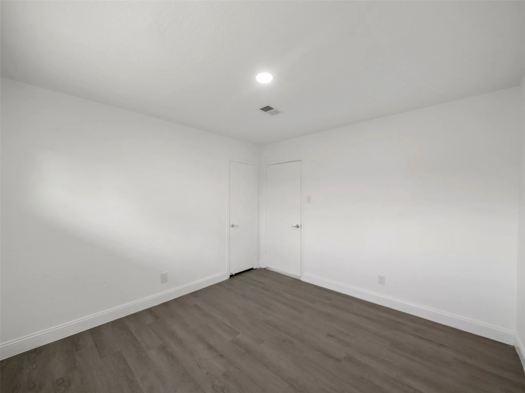 Recessed ceiling lighting, wood-finish flooring, and white walls