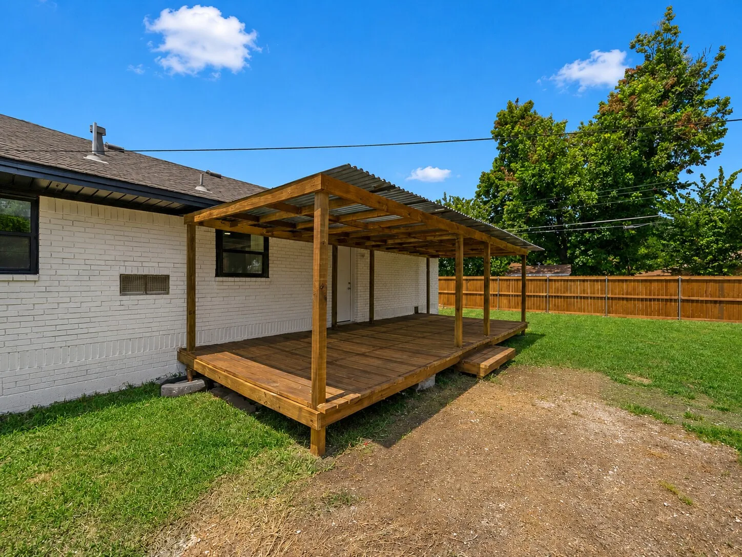 Wooden deck with a corrugated metal patio cover and privacy fencing