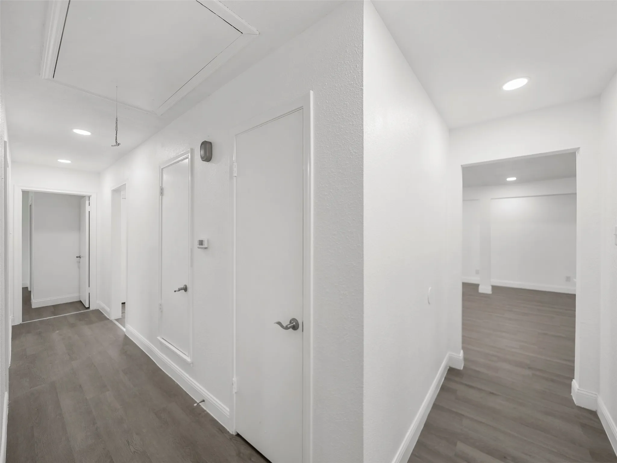 Recessed ceiling lighting illuminates the hallway with wood-finish flooring
