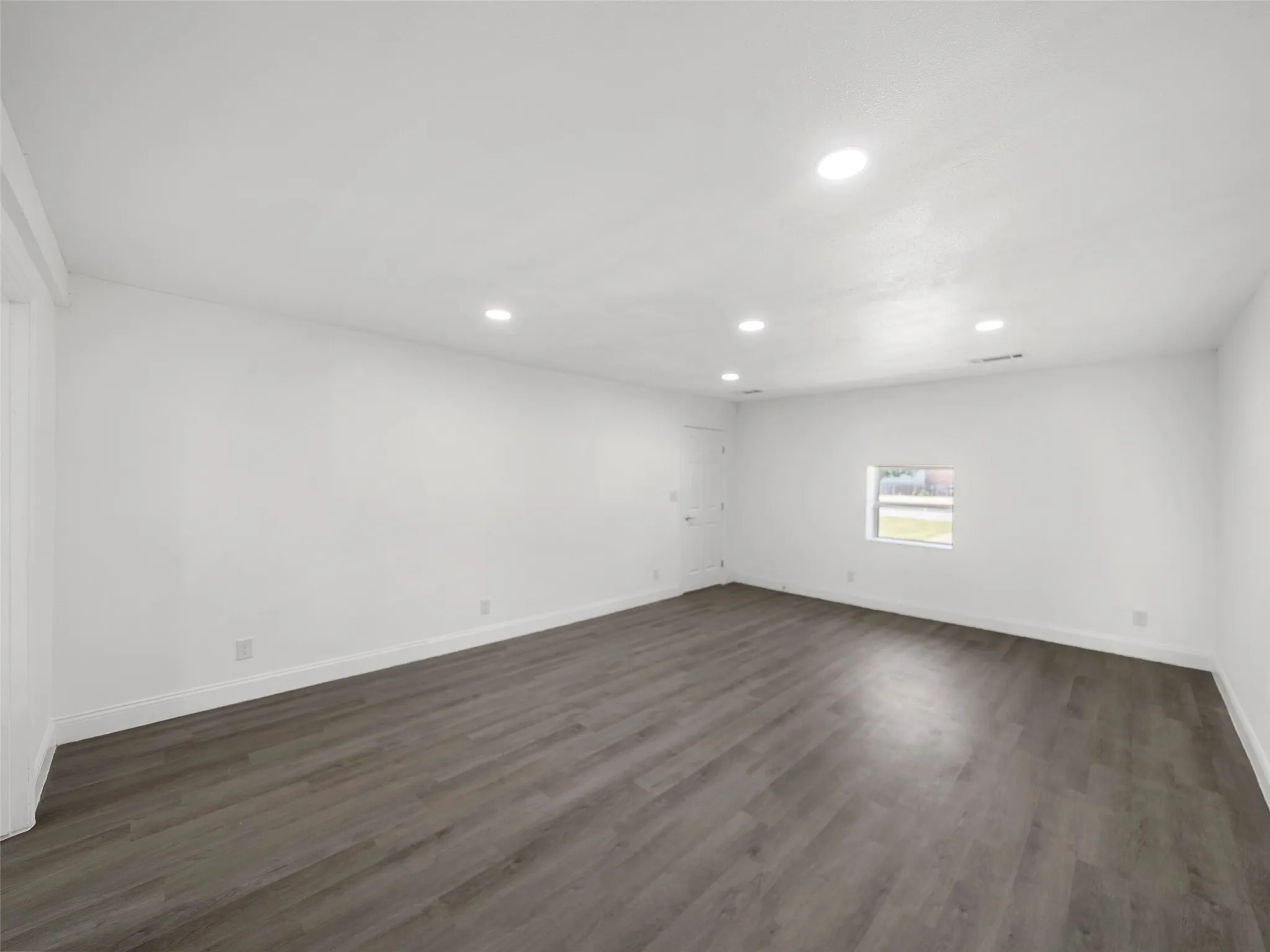Recessed ceiling lighting, wood-finish flooring, white walls, white trim, and a single window