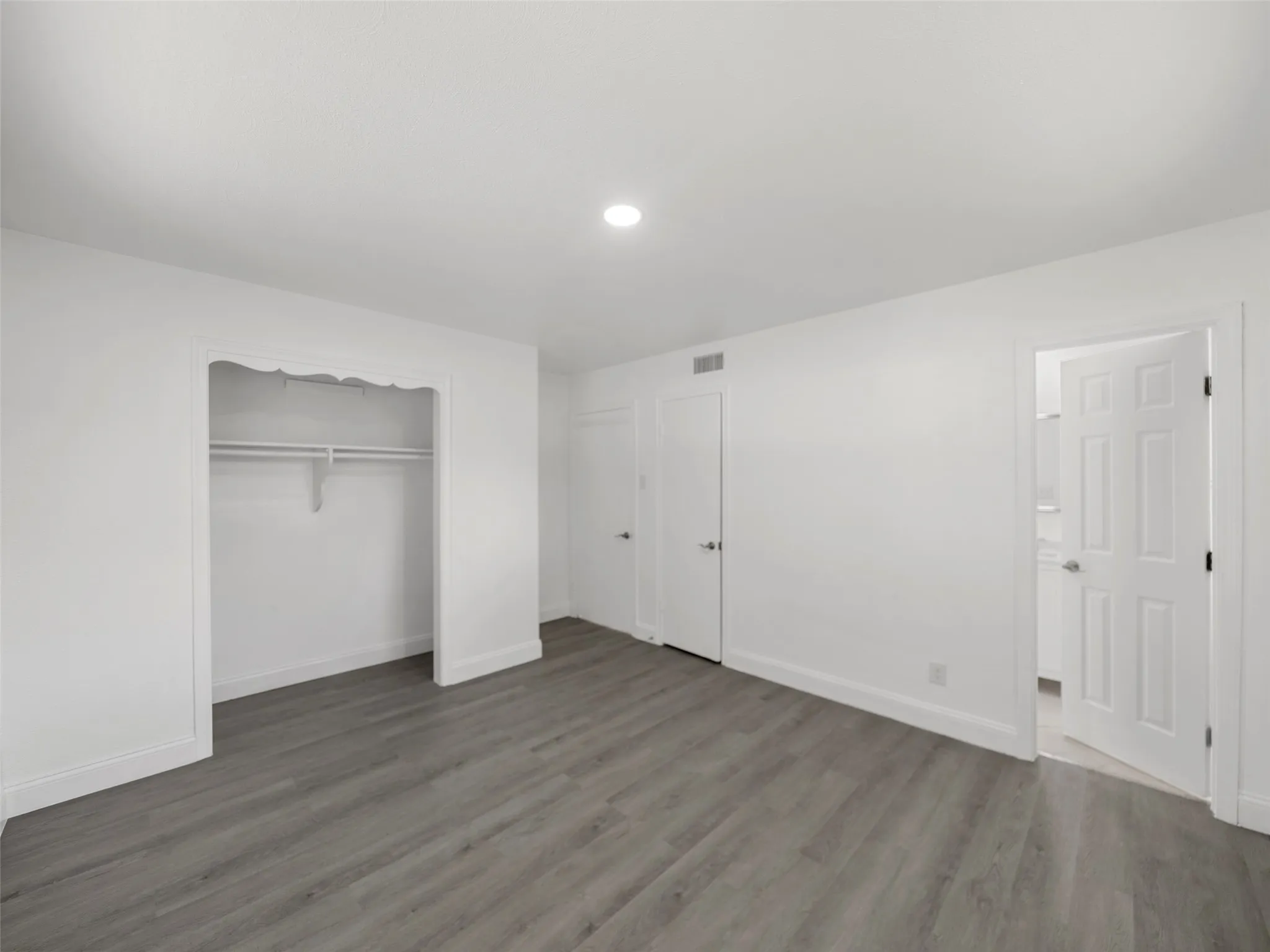 Recessed lighting, wood-finish flooring, white trim, and a built-in closet with shelving