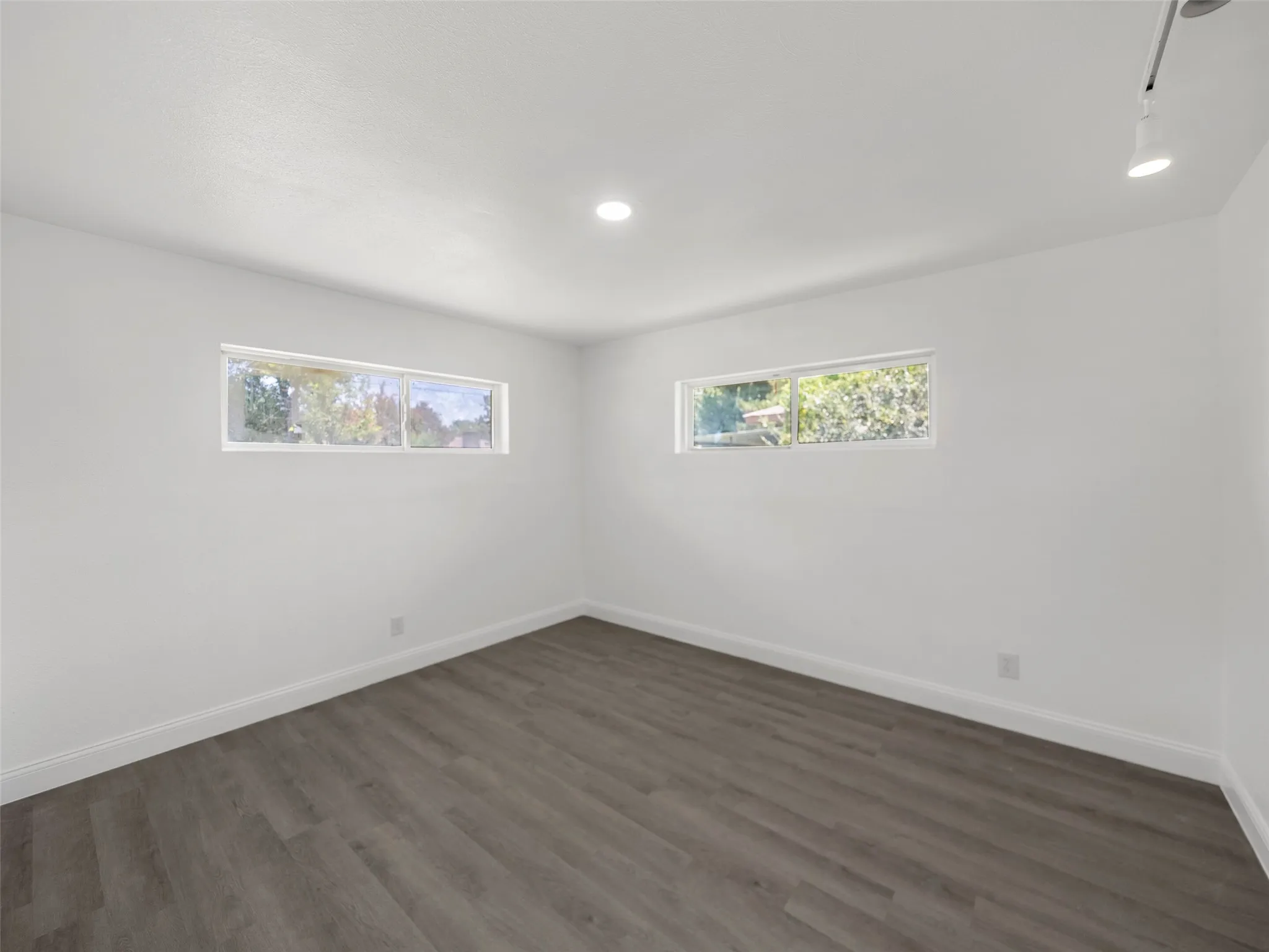 Recessed lighting, wood-finish flooring, and white baseboards