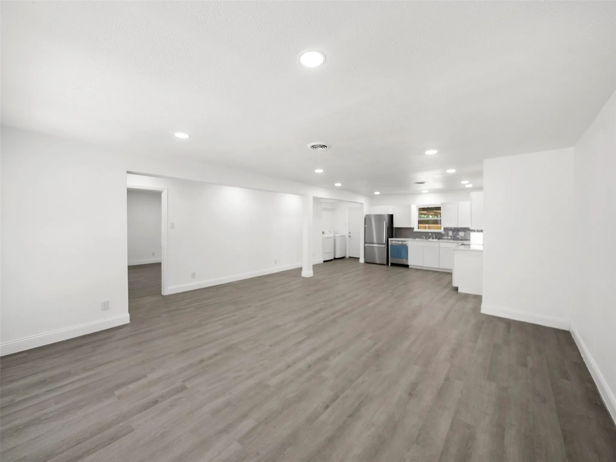 Open-concept living area with wood-finish flooring, recessed lighting, and white walls