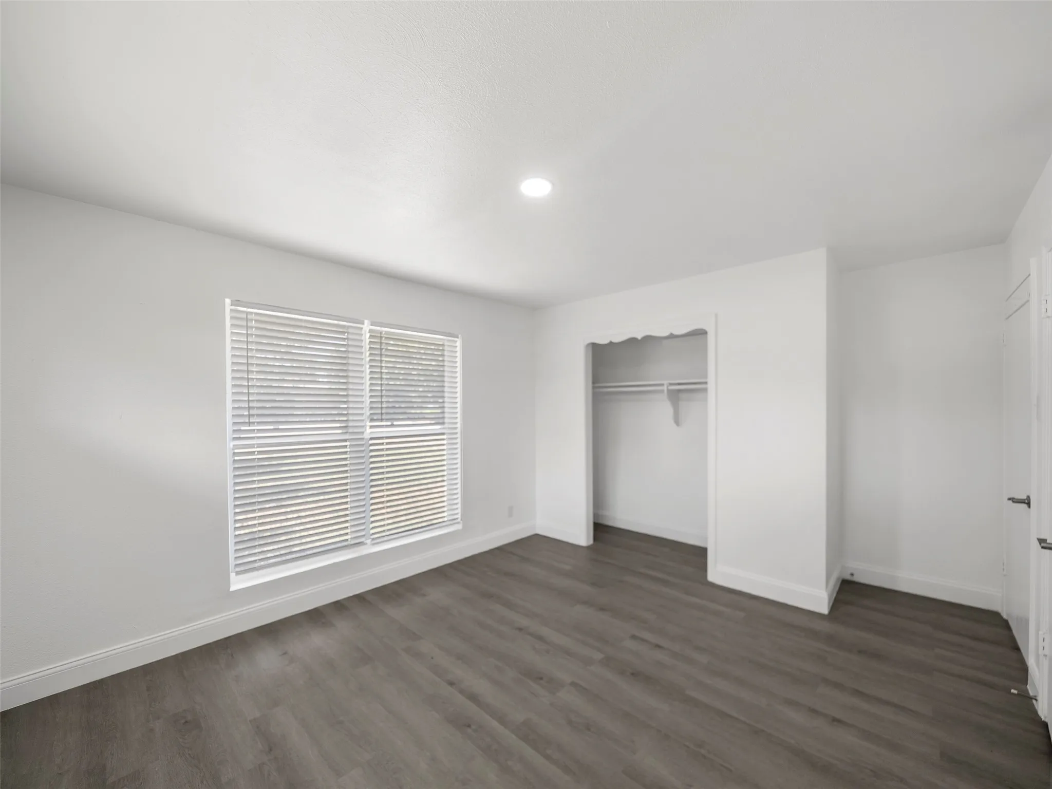 Wood-finish flooring, recessed lighting, and a built-in closet with shelving
