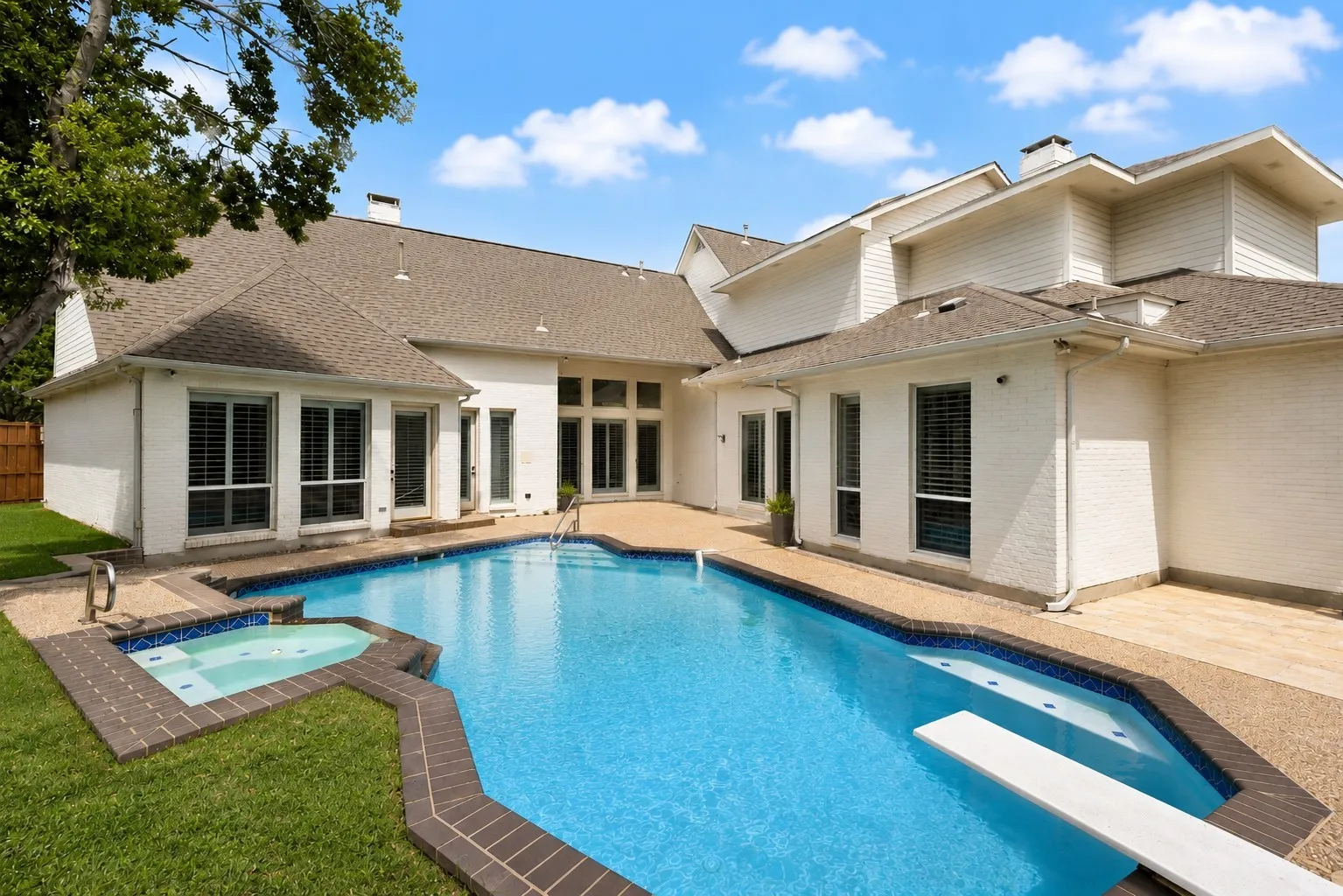 Exterior featuring a multi-level roofline, a swimming pool with a diving board, and an integrated spa