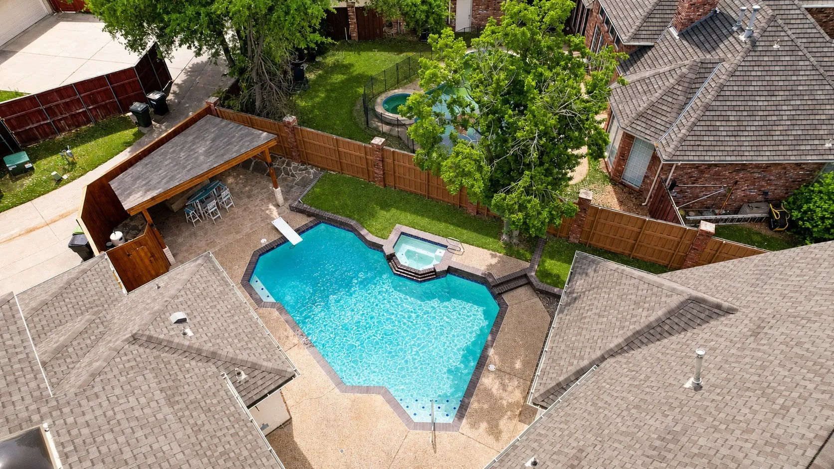 Geometric swimming pool with integrated spa, diving board, and surrounding concrete patio