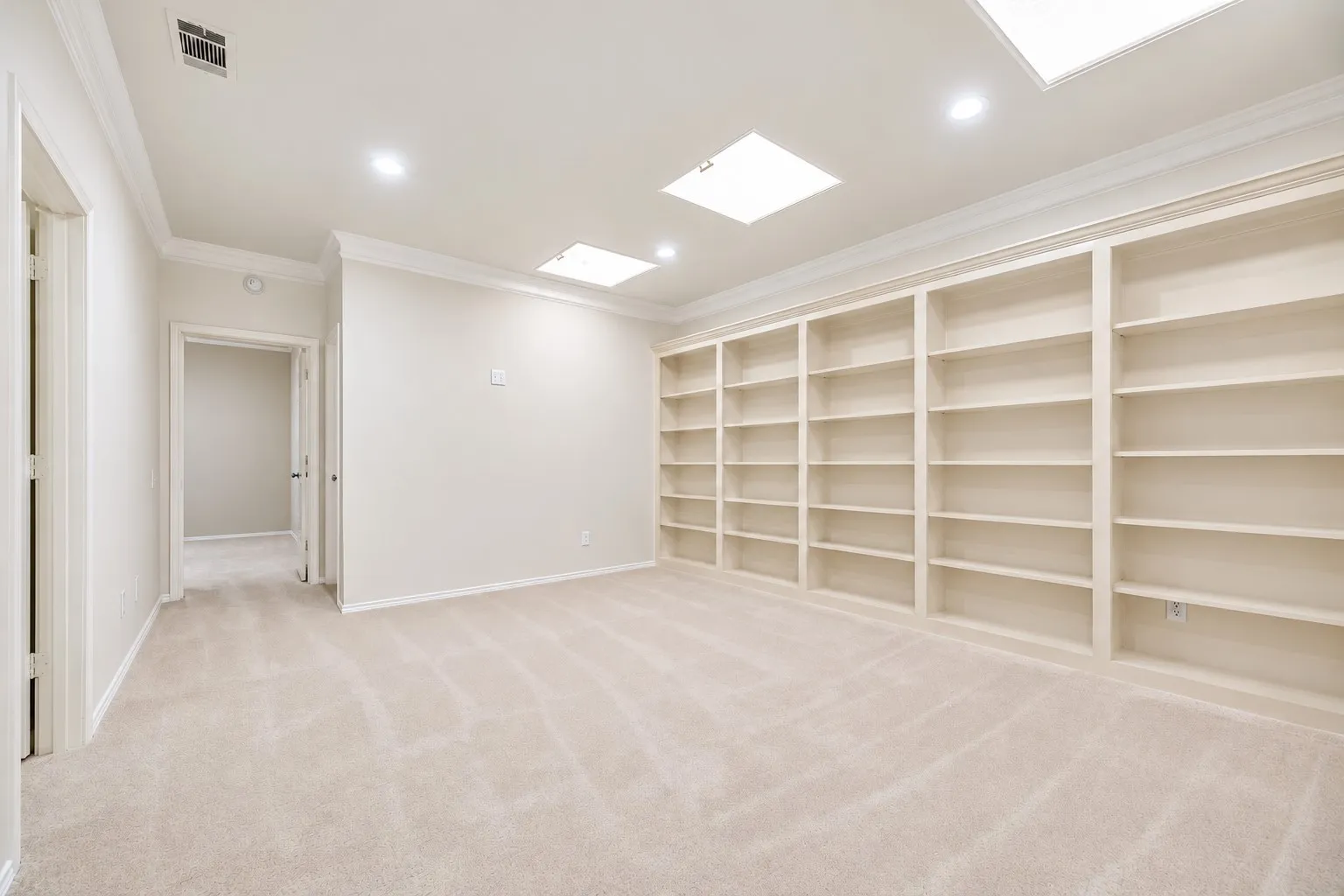 Built-in shelving, recessed lighting, crown molding, and carpet flooring