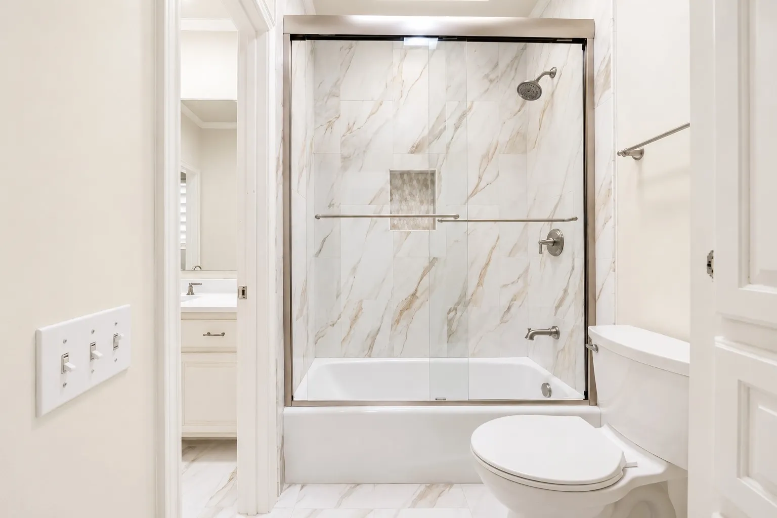 Tub and shower combination with glass enclosure, tile surround, and brushed nickel fixtures