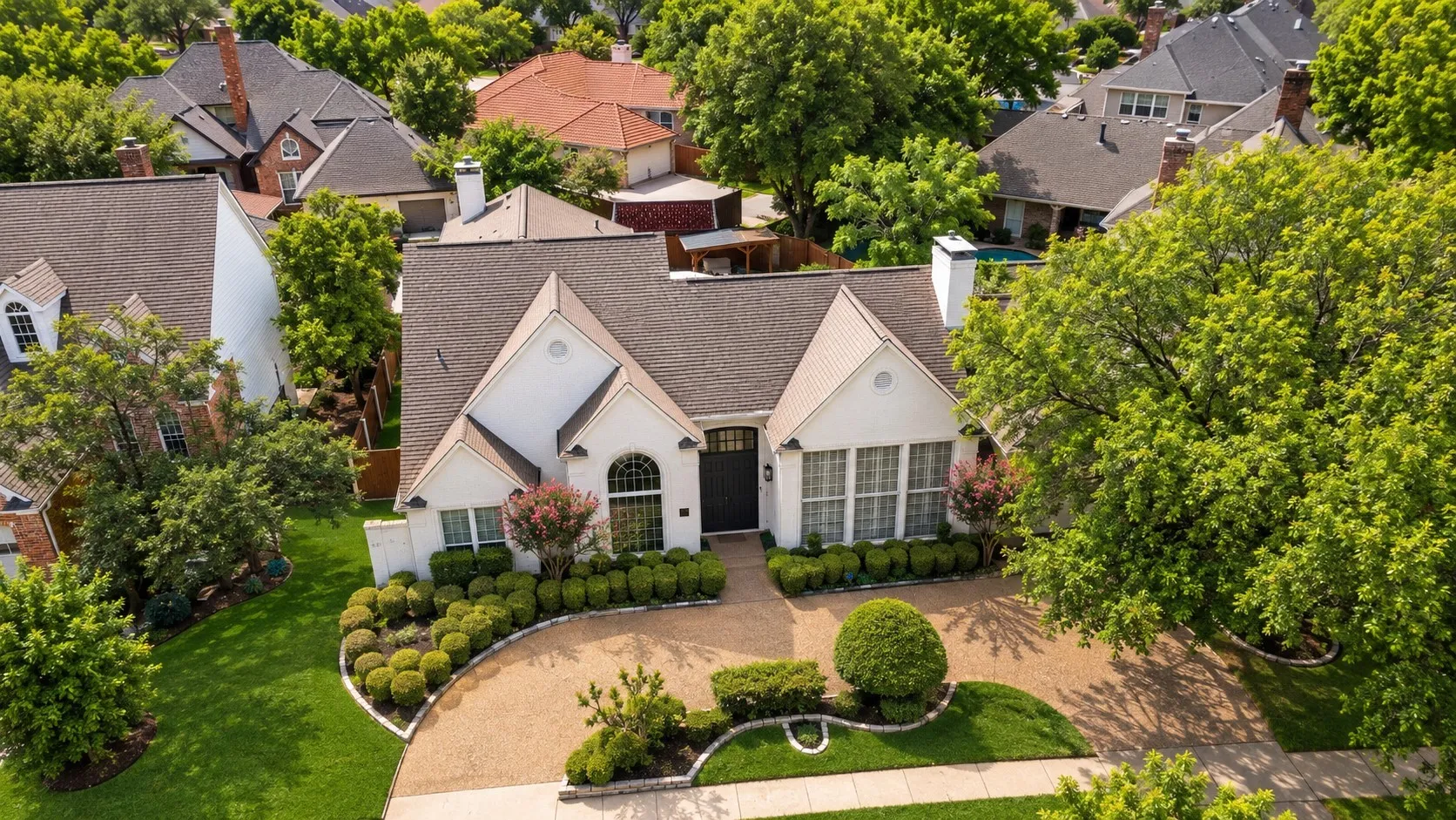White exterior residence featuring a gabled roof, arched entry, and well-maintained landscaping
