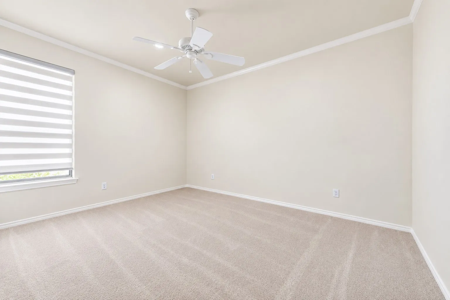 Recessed window with horizontal blinds, ceiling fan, crown molding, and neutral-toned carpet flooring