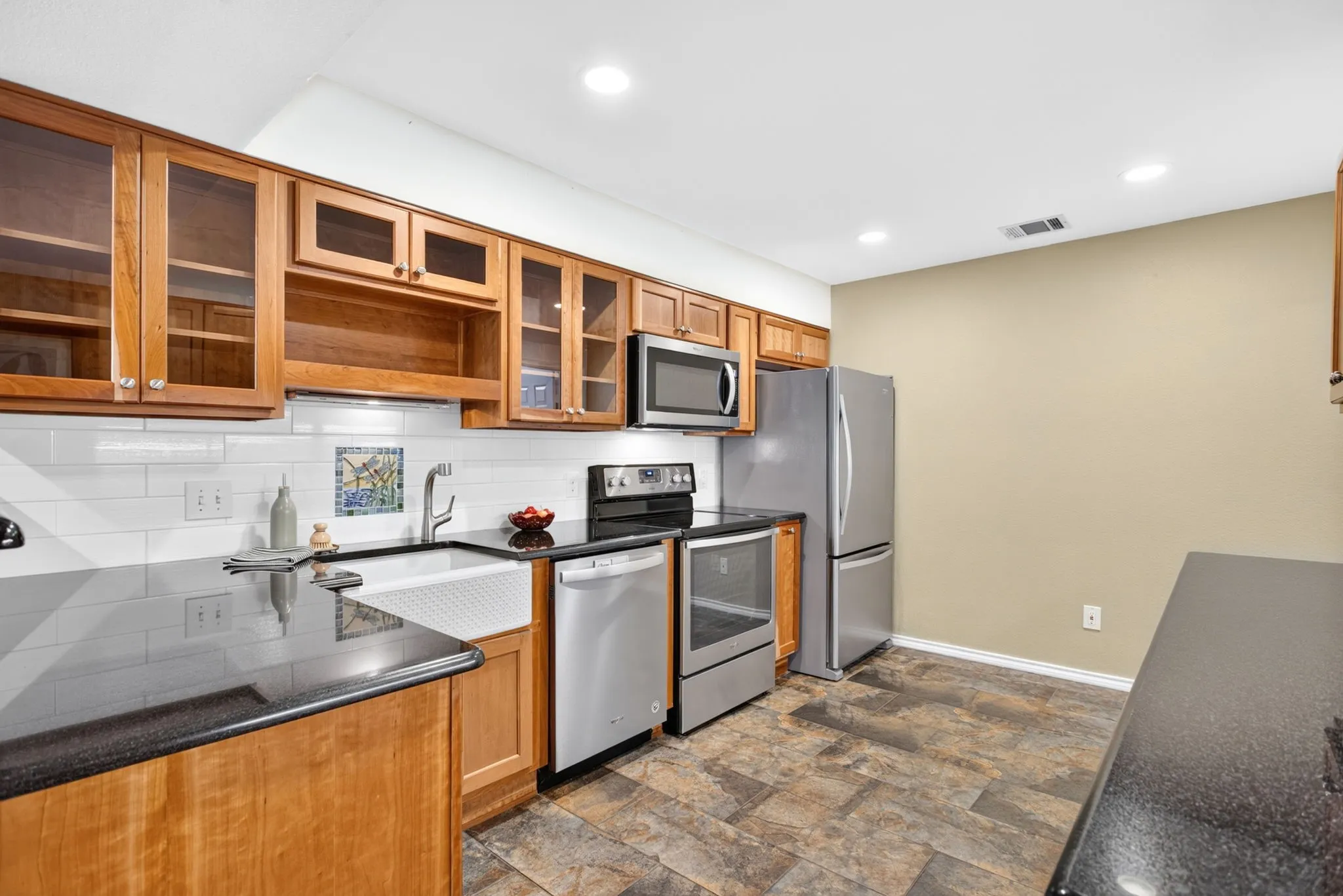 Everything in here is custom; glass front cabinets, under-cabinet lighting, arts and crafts-style mosaic backsplash vignettes.
