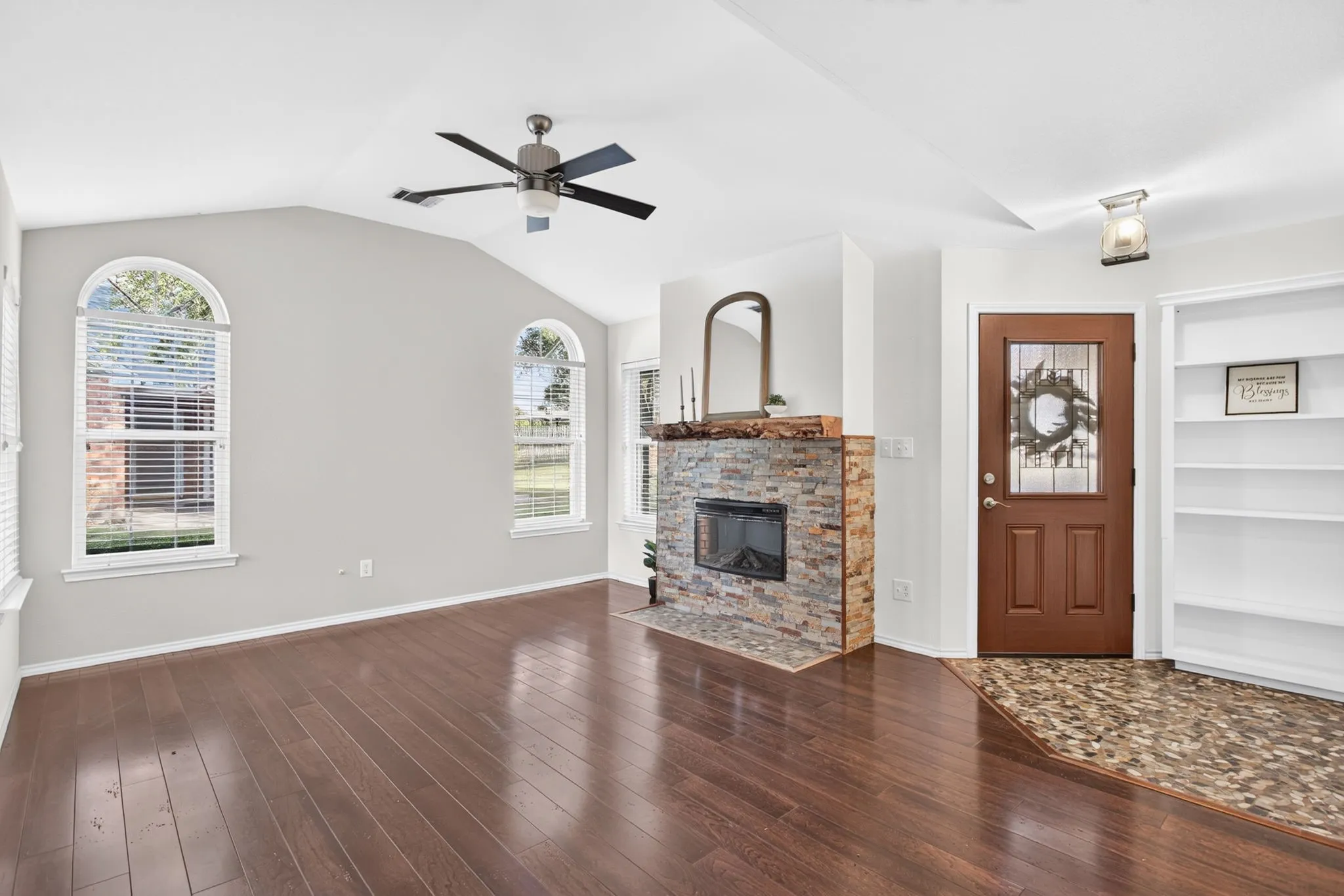 Gorgeous entryway with river rock foyer, Craftsman-style light, stacked stone fireplace and live edge mantel.