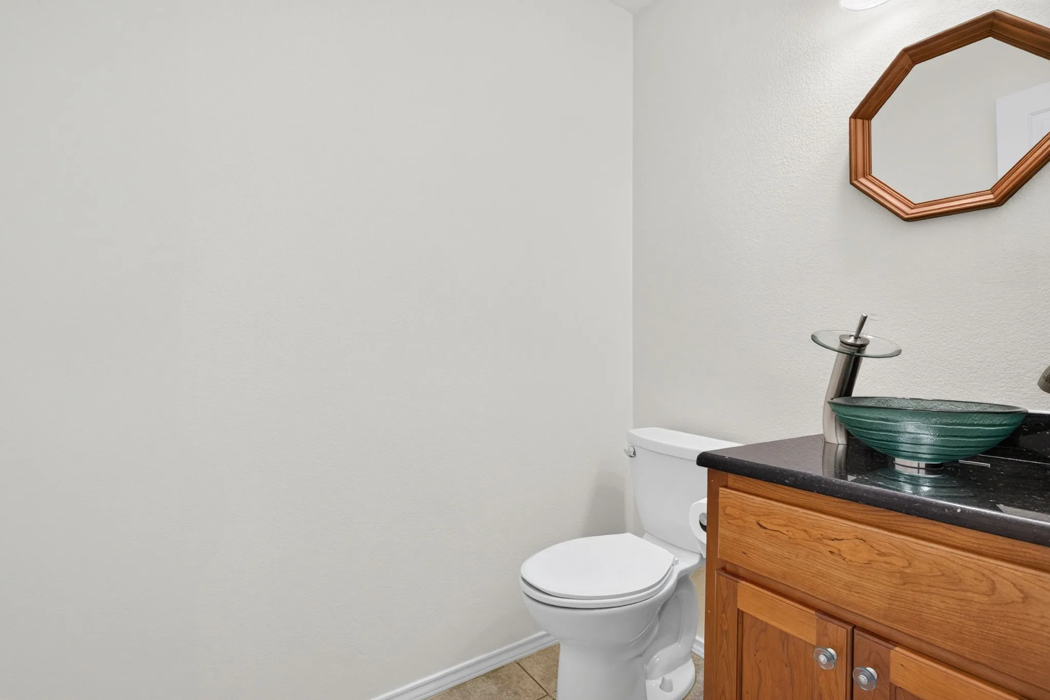 Powder bathroom with solid wood vanity, beautiful vessel sink with custom fixture and mirror.