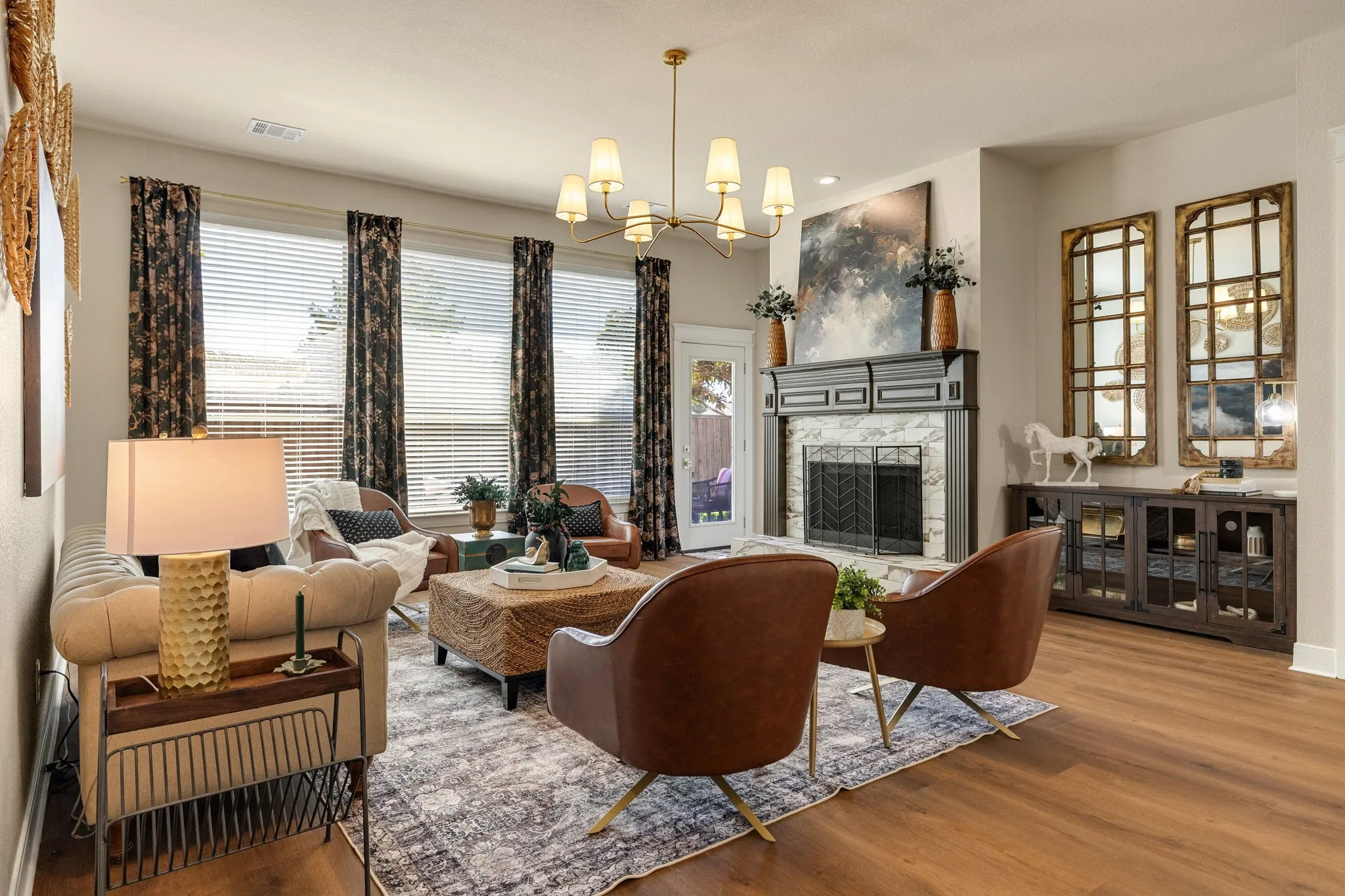 Living area with wood-finish flooring, a decorative fireplace with a marble-look surround and dark mantel, and multiple large windows