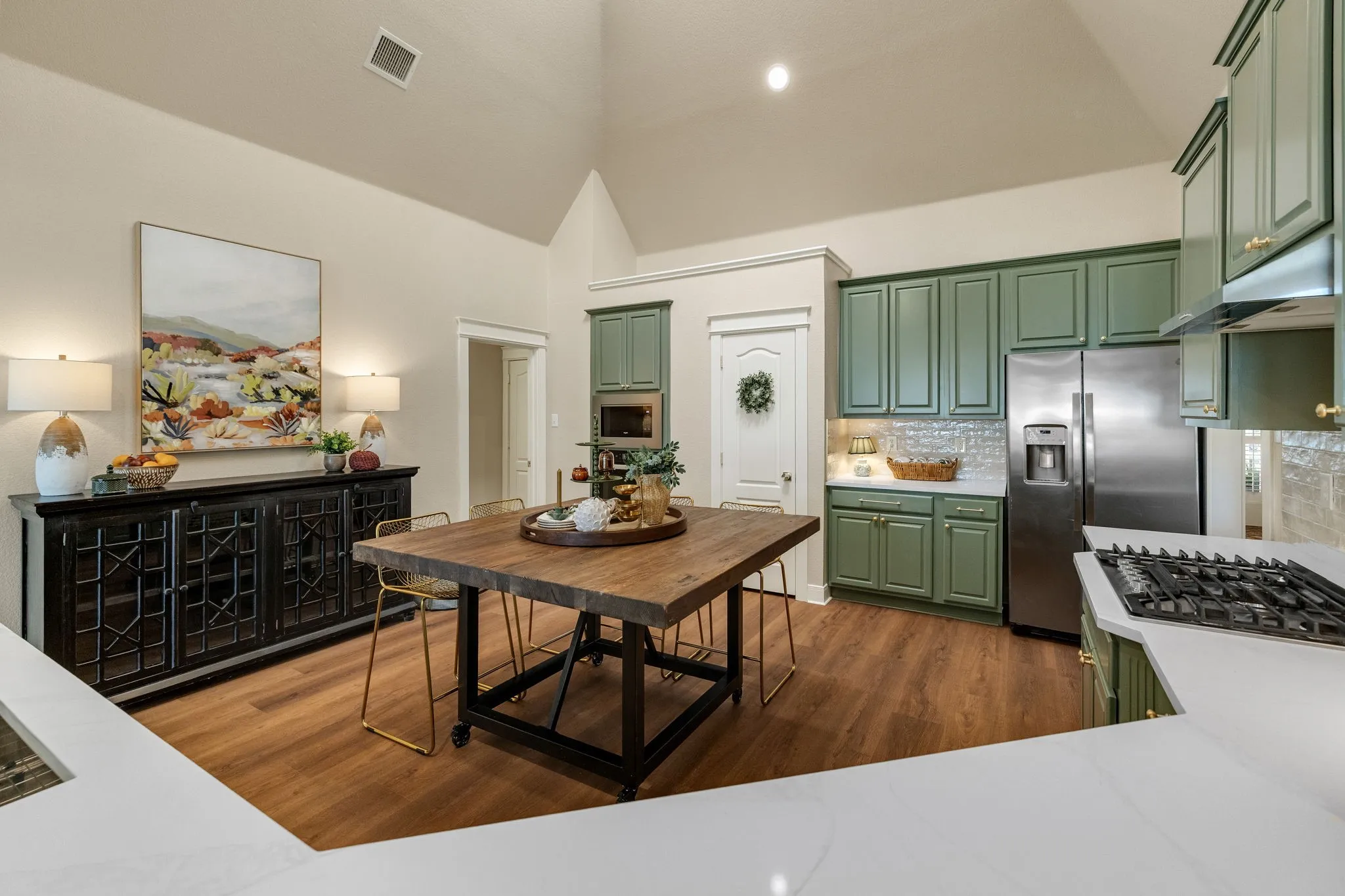 Vaulted ceilings, wood-finish flooring, white countertops, built-in stainless steel appliances, and green cabinetry