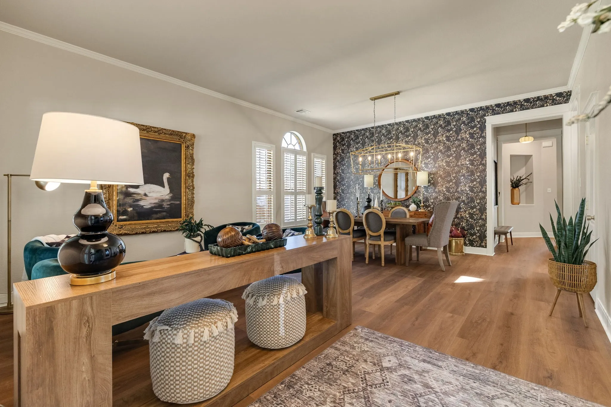 Wood-finish flooring throughout, framed arched windows, elegant crown molding, and a decorative accent wall