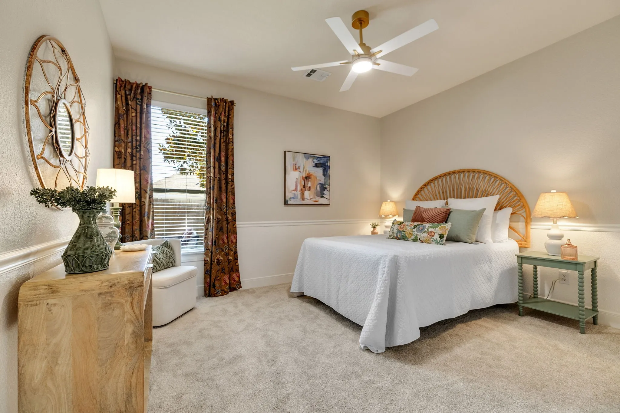 Neutral tone wall color, window with blinds and drapes, chair rail molding, ceiling fan with light fixture, and light-colored carpeting