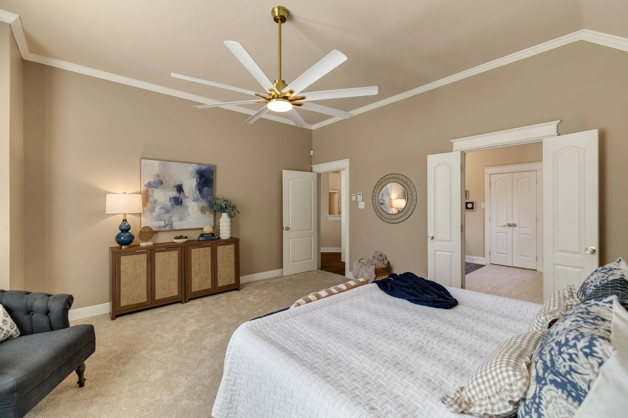 Vaulted ceiling with crown molding, ceiling fan with brushed gold accents, plush carpet flooring, and paneled interior doors