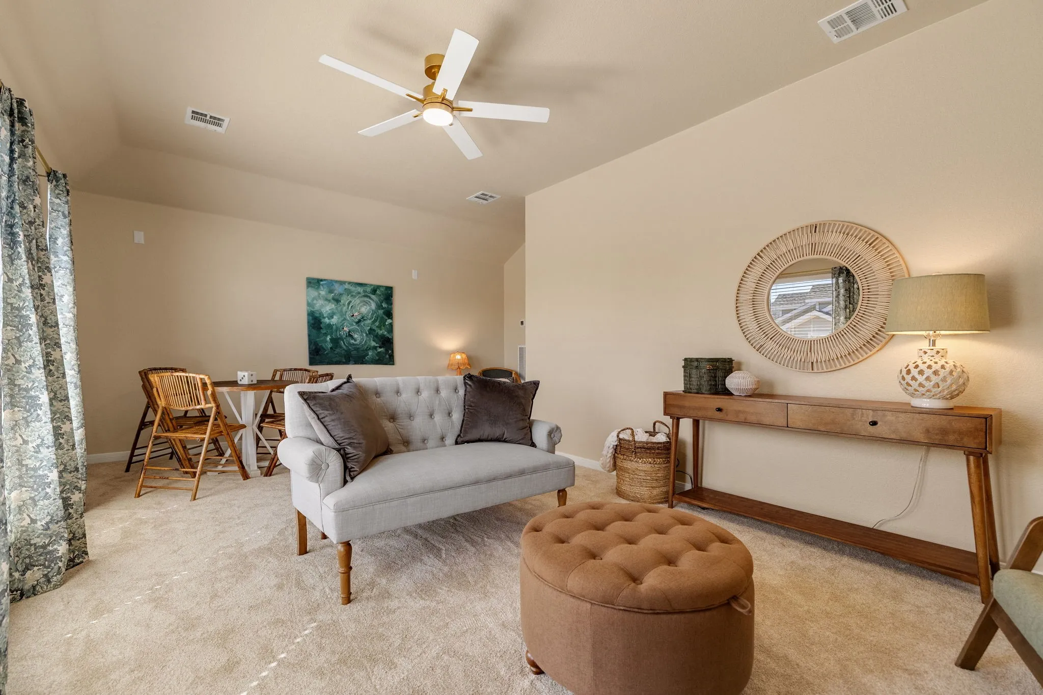 Open-concept living space with neutral tone walls, high vaulted ceilings, and a ceiling fan with light fixture