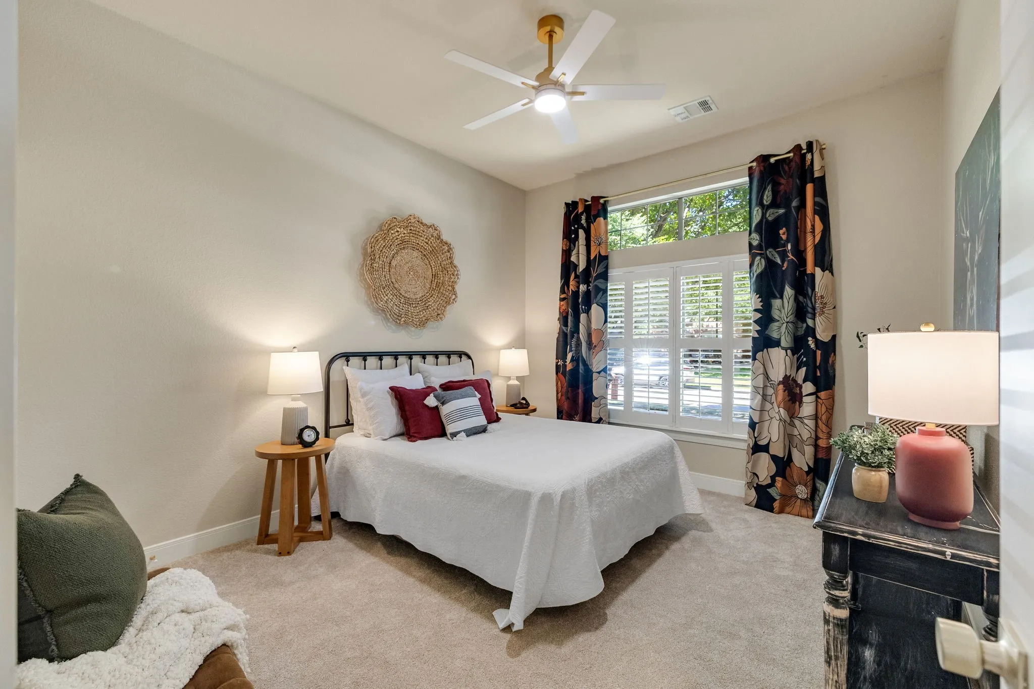 Recessed ceiling with an integrated fan and light fixture, window with plantation shutters and decorative curtains, and light-toned carpeting