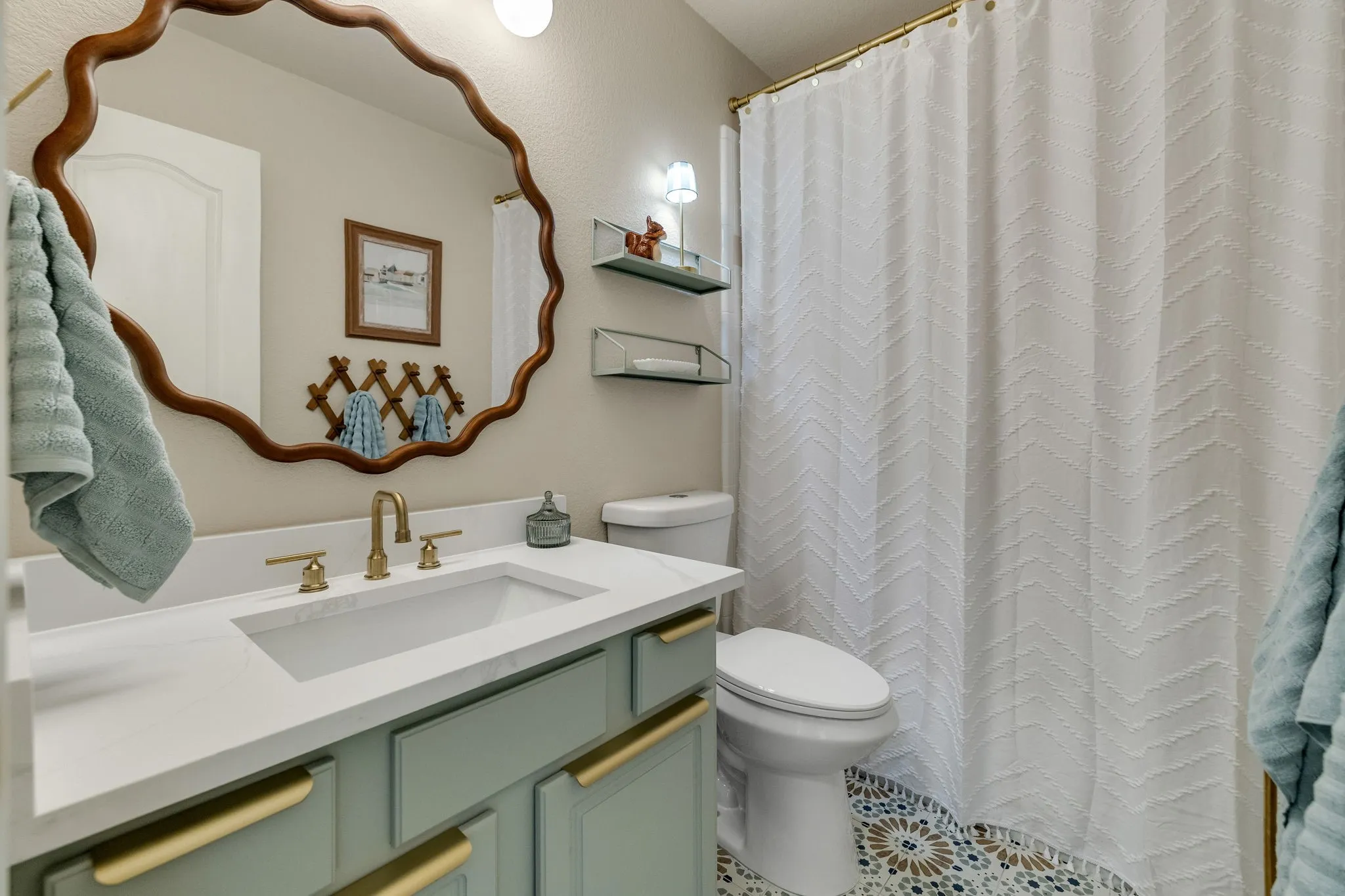 White vanity countertop with an integrated rectangular sink and brass-finish faucet