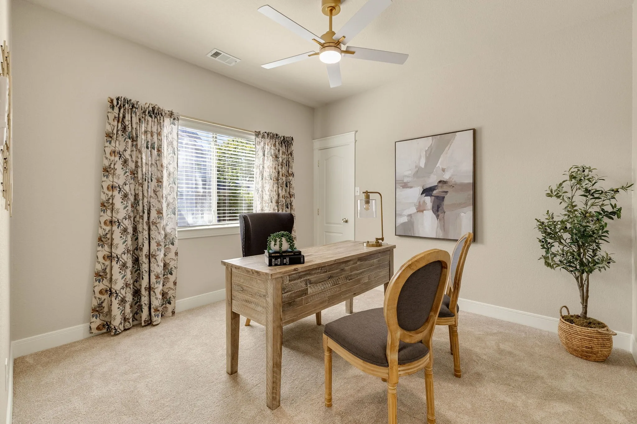 Single window with blinds, light-toned walls, gold and white ceiling fan, and light-toned carpet flooring