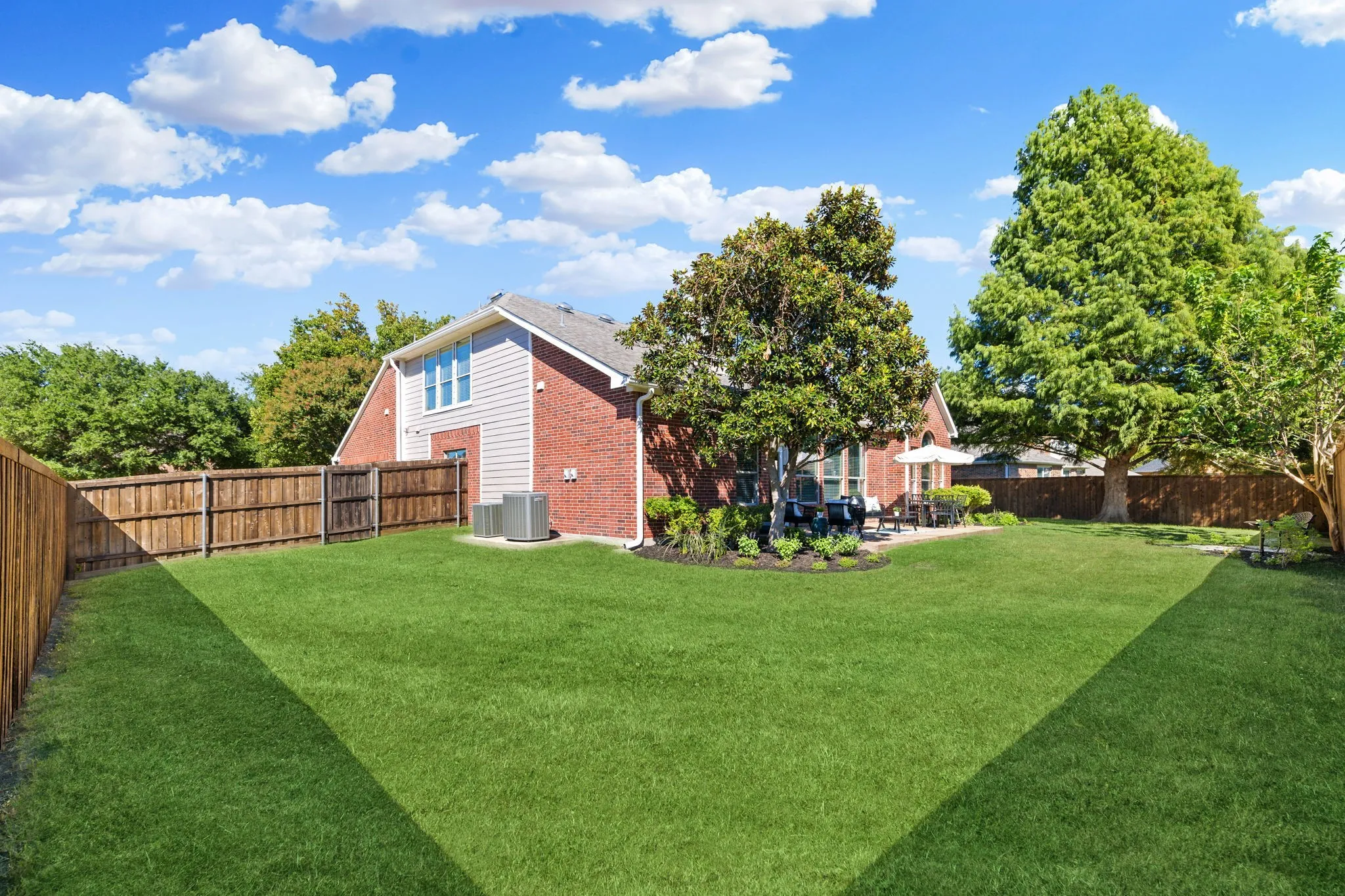 Expansive lawn with mature trees and a privacy fence