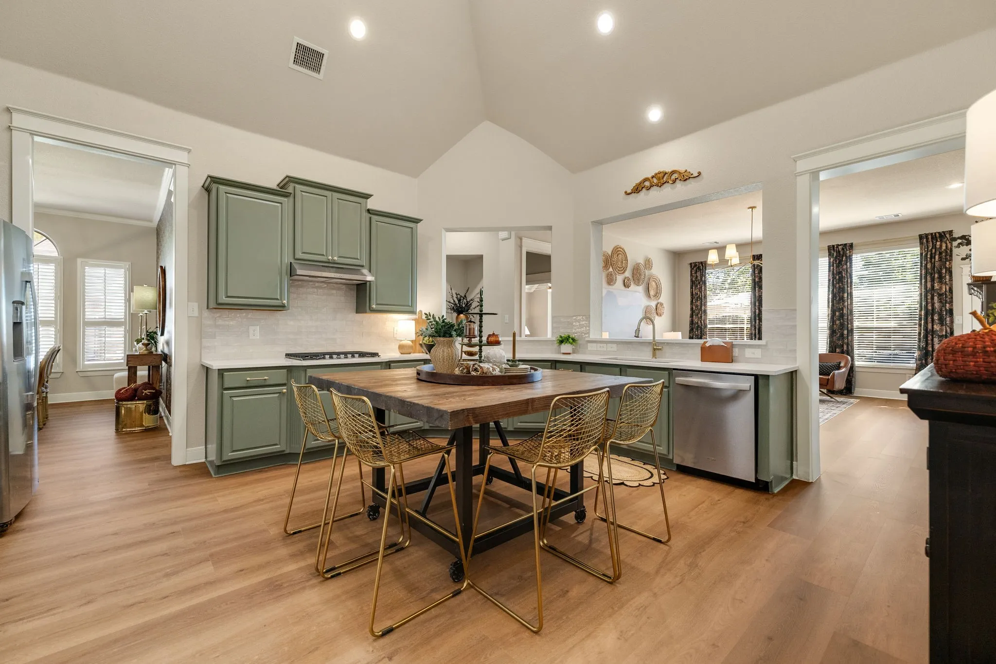 Kitchen featuring vaulted ceilings, wood-finish flooring, recessed lighting, sage-colored cabinetry, and stainless steel appliances