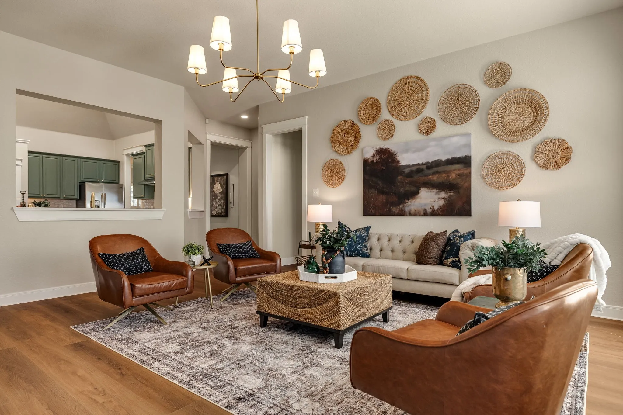 Spacious living area featuring wood-finish flooring, a contemporary chandelier, and a pass-through opening to the kitchen with green cabinetry
