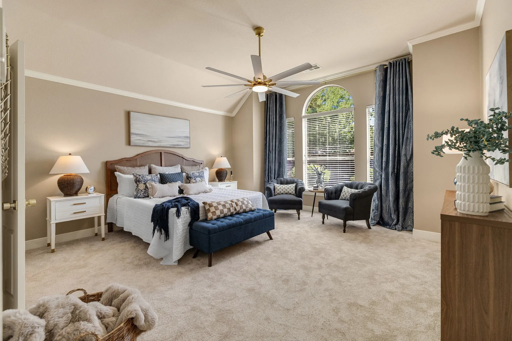 Vaulted ceiling with crown molding, ceiling fan, and arched windows