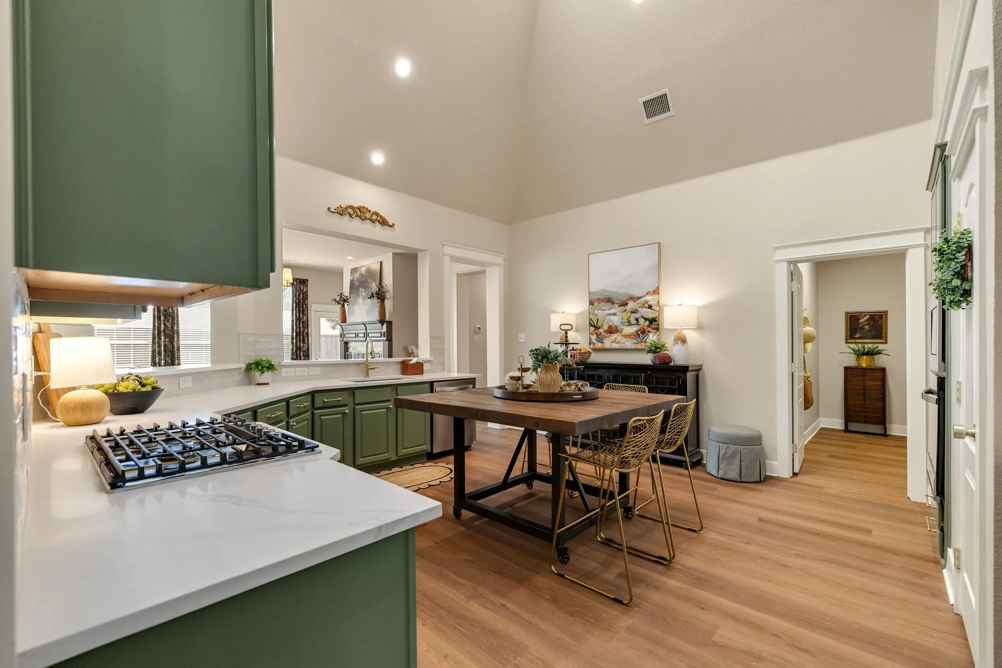Gourmet kitchen featuring a gas range, green cabinetry, white countertops, wood-finish flooring, and a vaulted ceiling