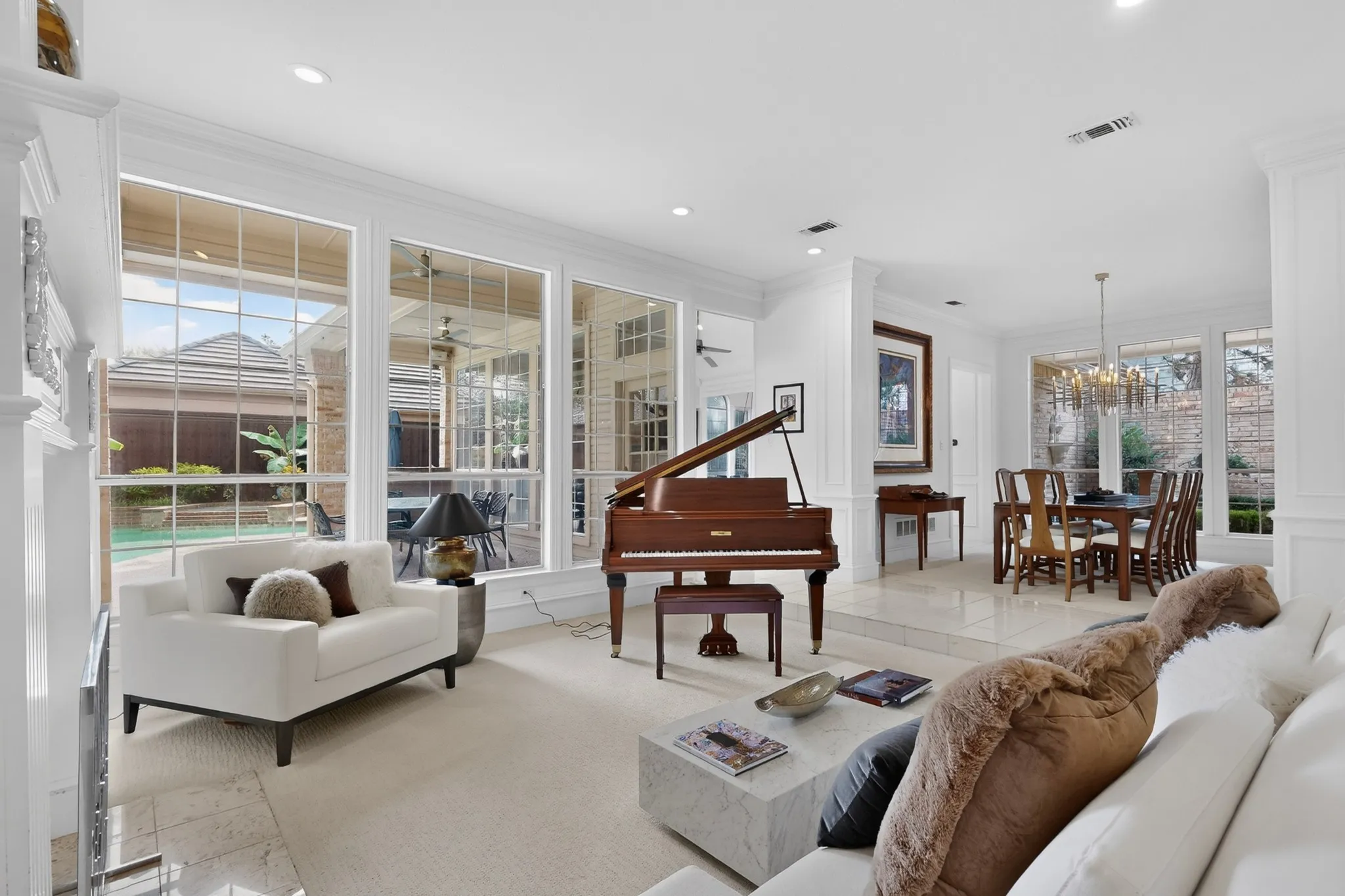 Expansive windows with transom details, recessed lighting, crown molding, and a dining area with a chandelier