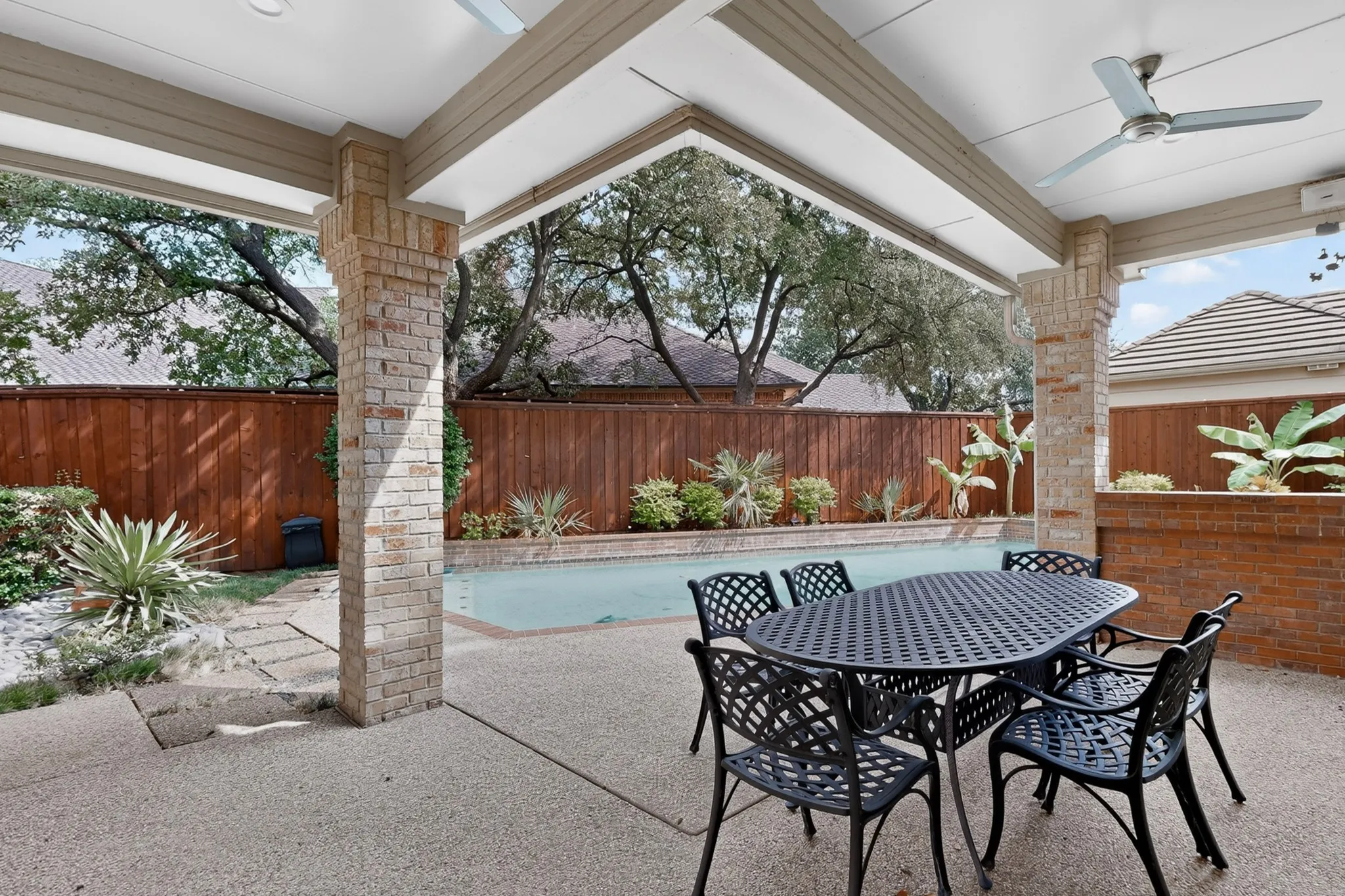 Covered patio with exposed aggregate flooring, brick columns, and ceiling fans