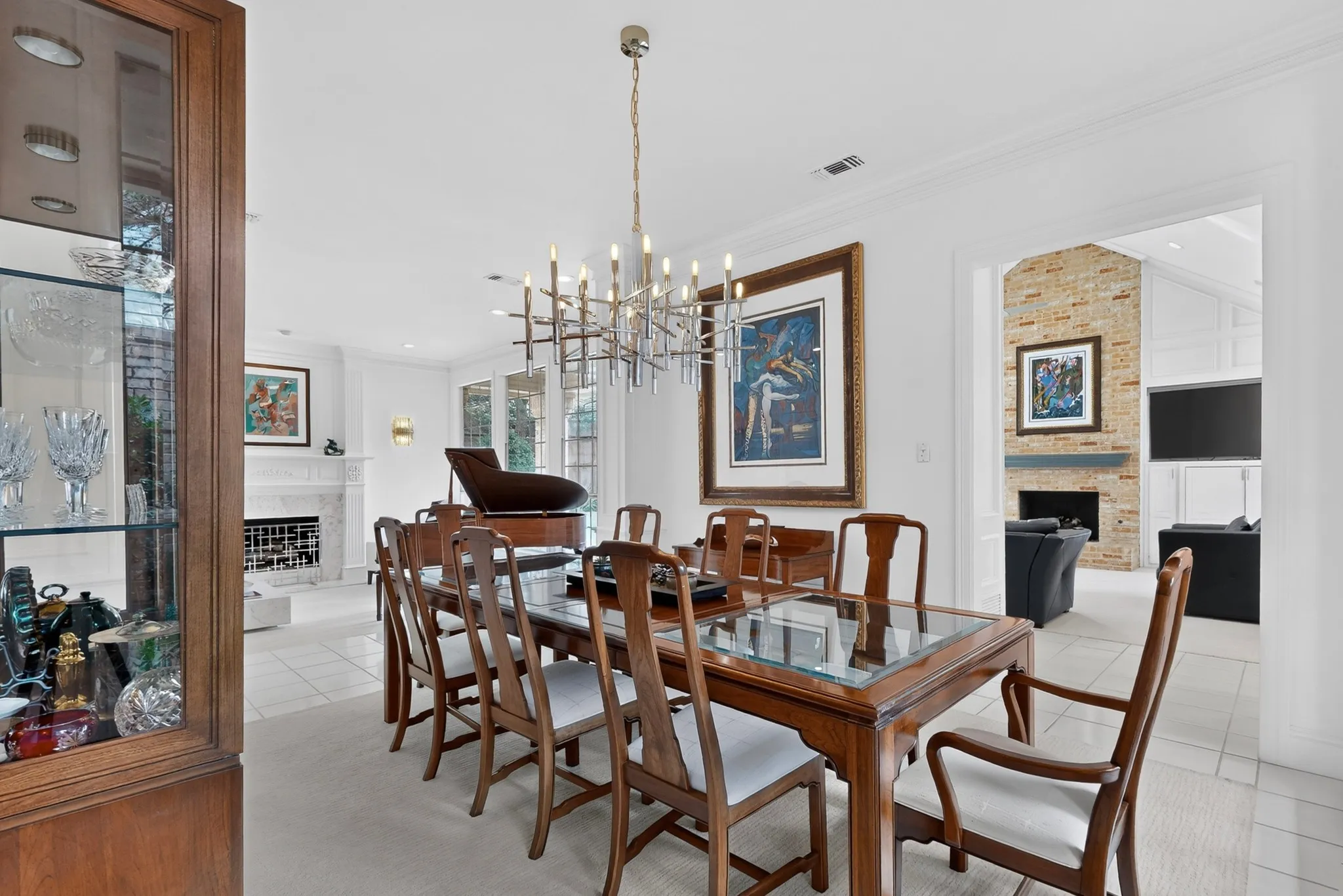 White wall finishes, crown molding, and a contemporary chandelier illuminate this space
